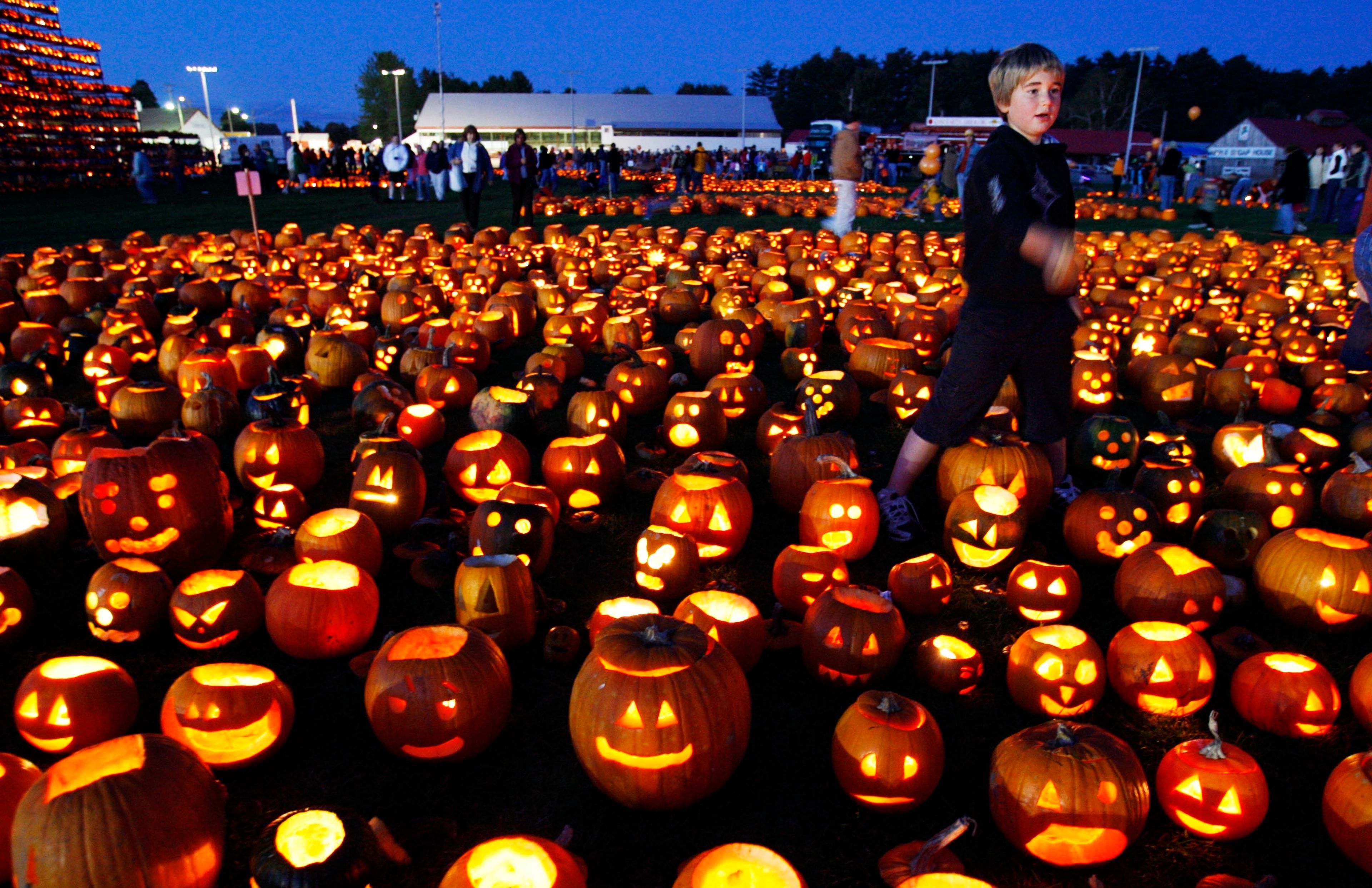 FILE - A boy finishes lighting a patch of jack-o-lanterns at the Camp Sunshine Maine Pumpkin Festival, Oct. 4, 2008, in Cumberland, Maine. (AP Photo/Robert F. Bukaty, File)