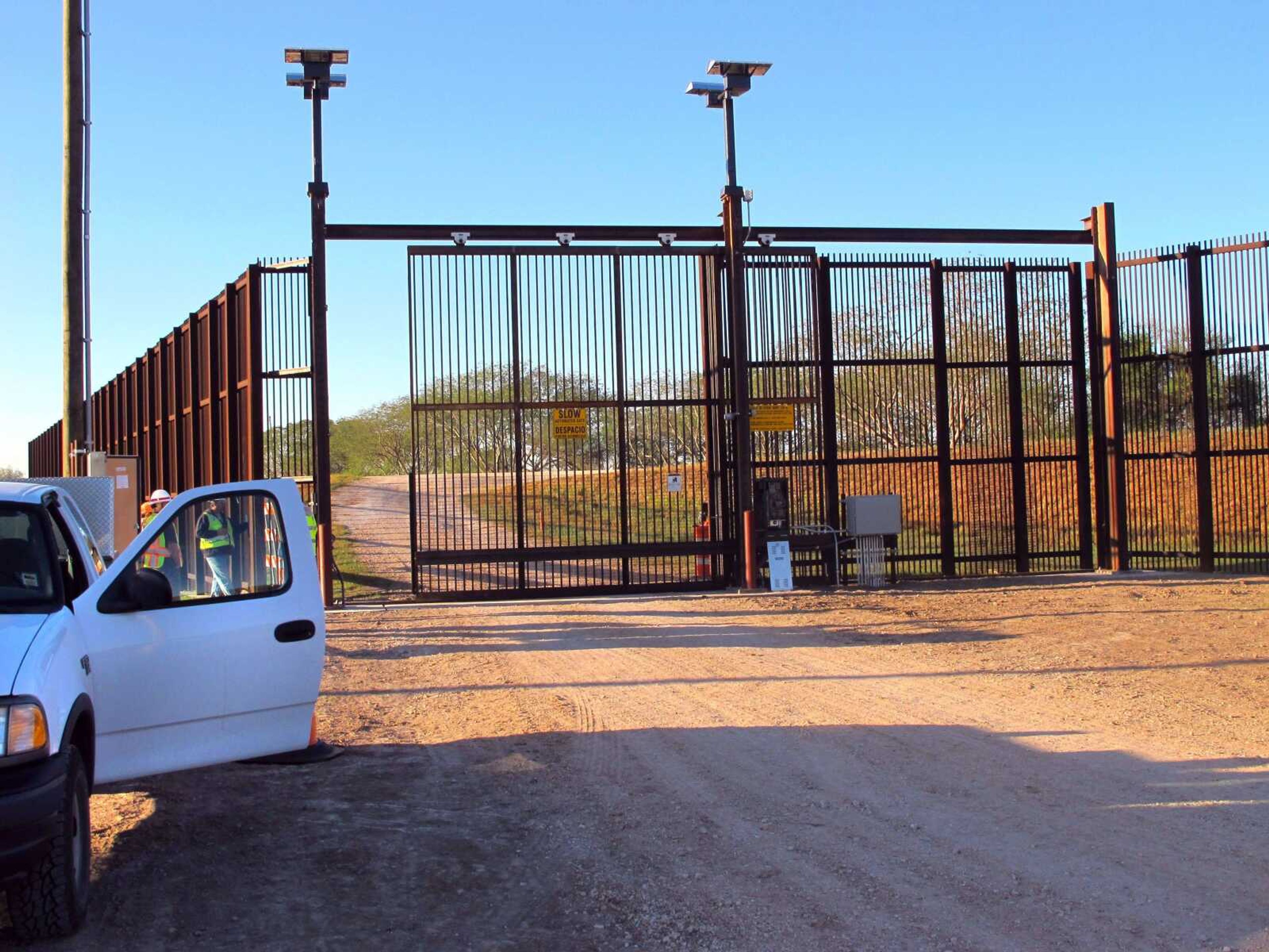 Government contractors test a new gate in the border fence Jan. 27 in Brownsville, Texas. A year after completion of the border fence, the government is installing 44 gates in South Texas. (Chris Sherman ~ Associated Press)