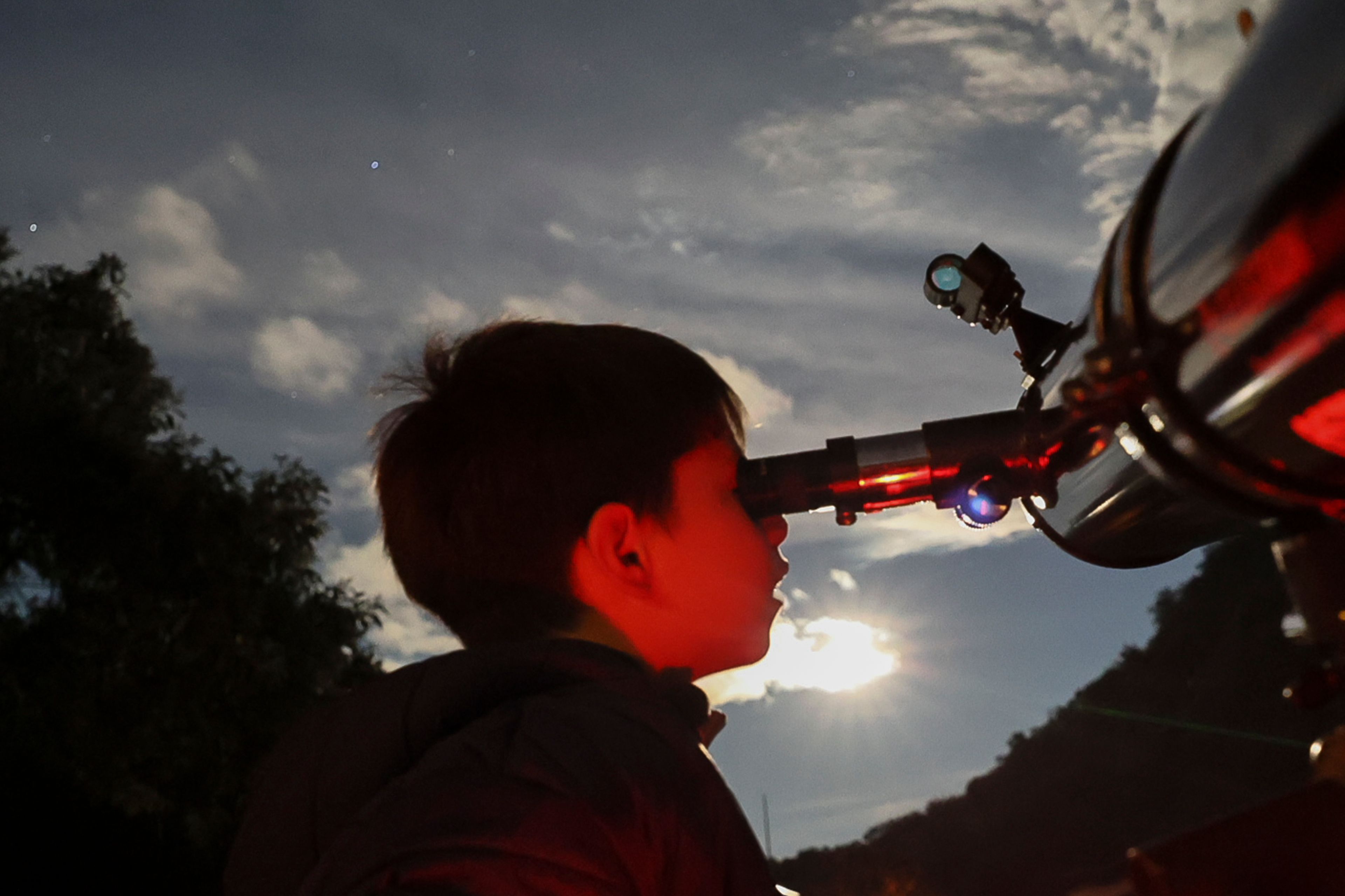 A youth looks through a telescope during a stargazing and comet-watching gathering at Joya-La Barreta Ecological Park in Queretaro, Mexico, Saturday, Oct. 19, 2024. (AP Photo/Ginnette Riquelme)