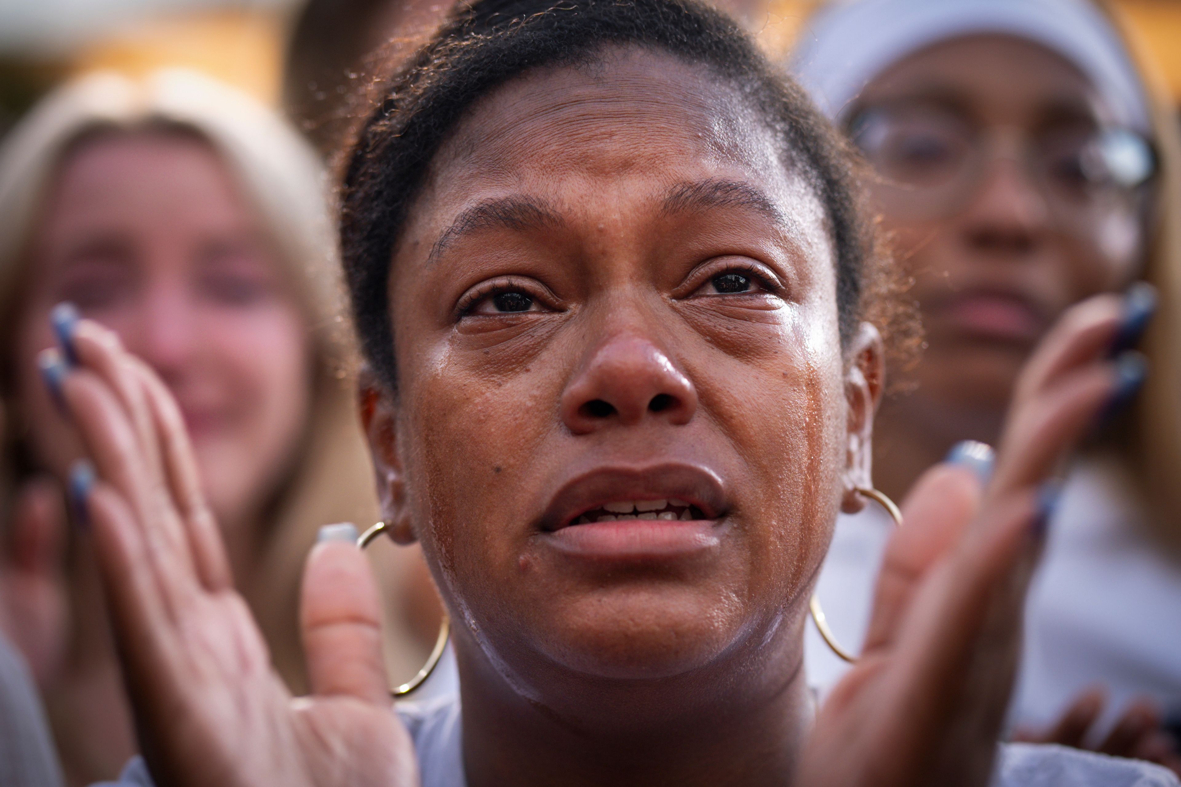 With tears streaming down her face, a supporter of Democratic presidential nominee Vice President Kamala Harris applauds as Harris delivers a concession speech after the 2024 presidential election, Wednesday, Nov. 6, 2024, on the campus of Howard University in Washington. (AP Photo/Jacquelyn Martin)