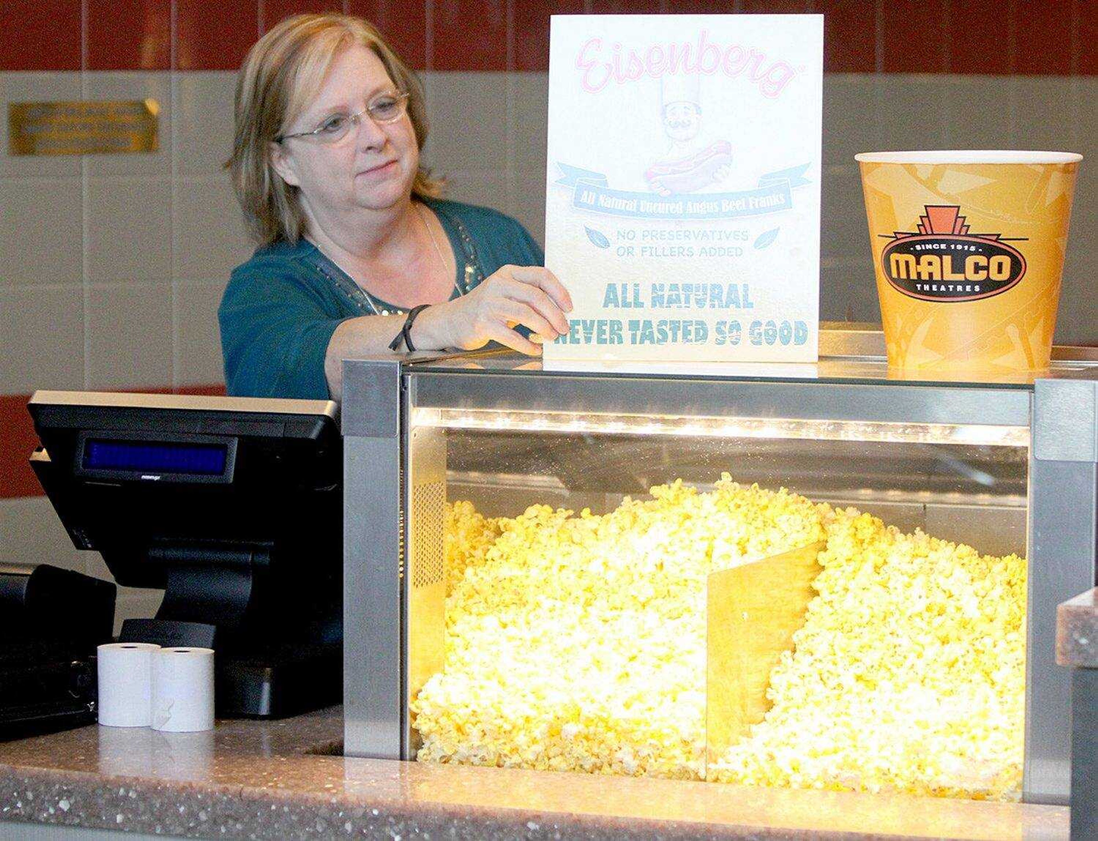 Patti Kenser, general manager of the new Malco Sikeston Cinema & Grill, sets up a display at the concession counter Tuesday morning. The theater opened Thursday at 1218 Cinema Drive off U.S. 60 and Hennings Road in the Cotton Ridge Development.