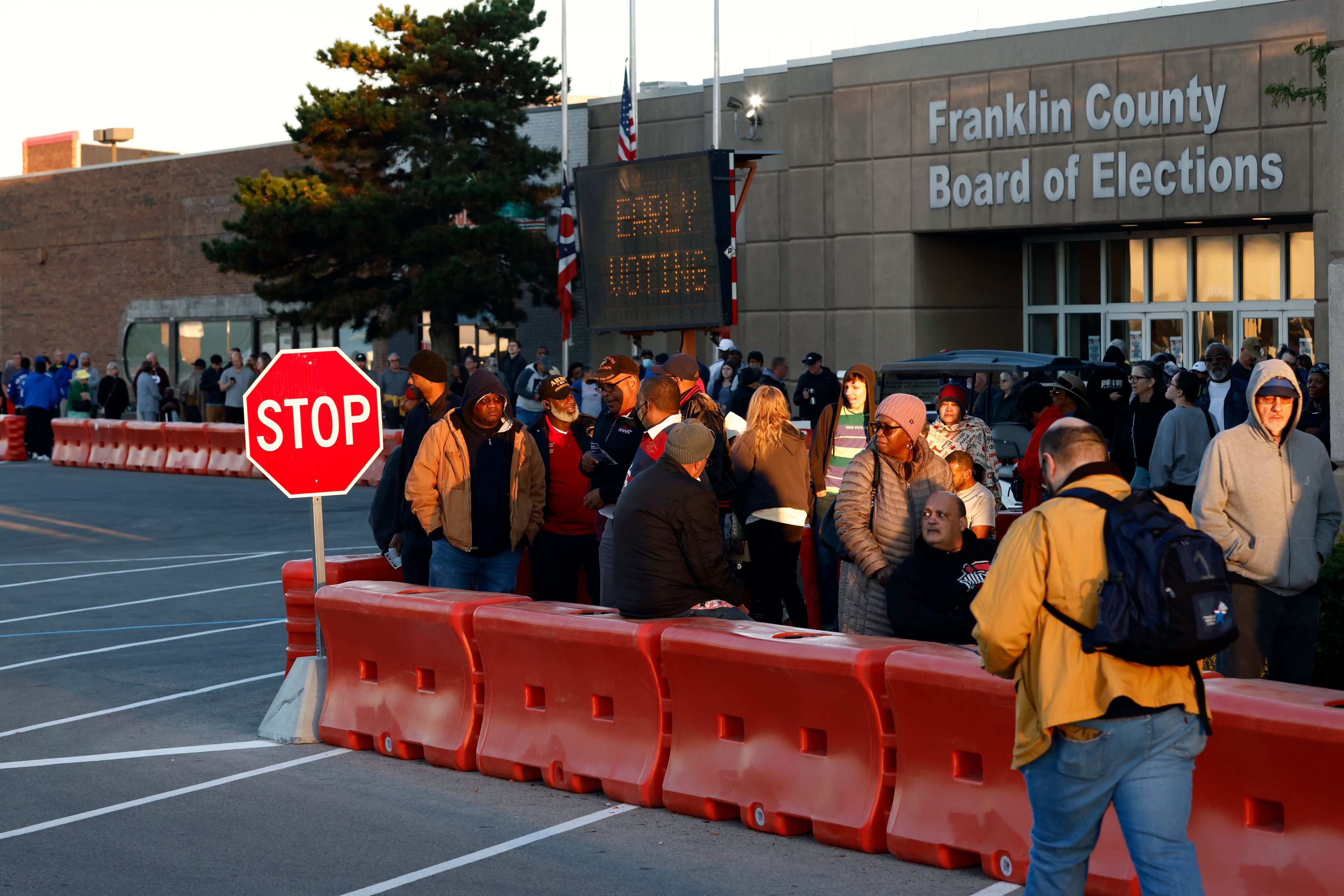 Voters wait outside of the Franklin County Board of Elections for the first day of in person early voting in Columbus, Ohio, Tuesday, Oct. 8, 2024. (AP Photo/Paul Vernon)