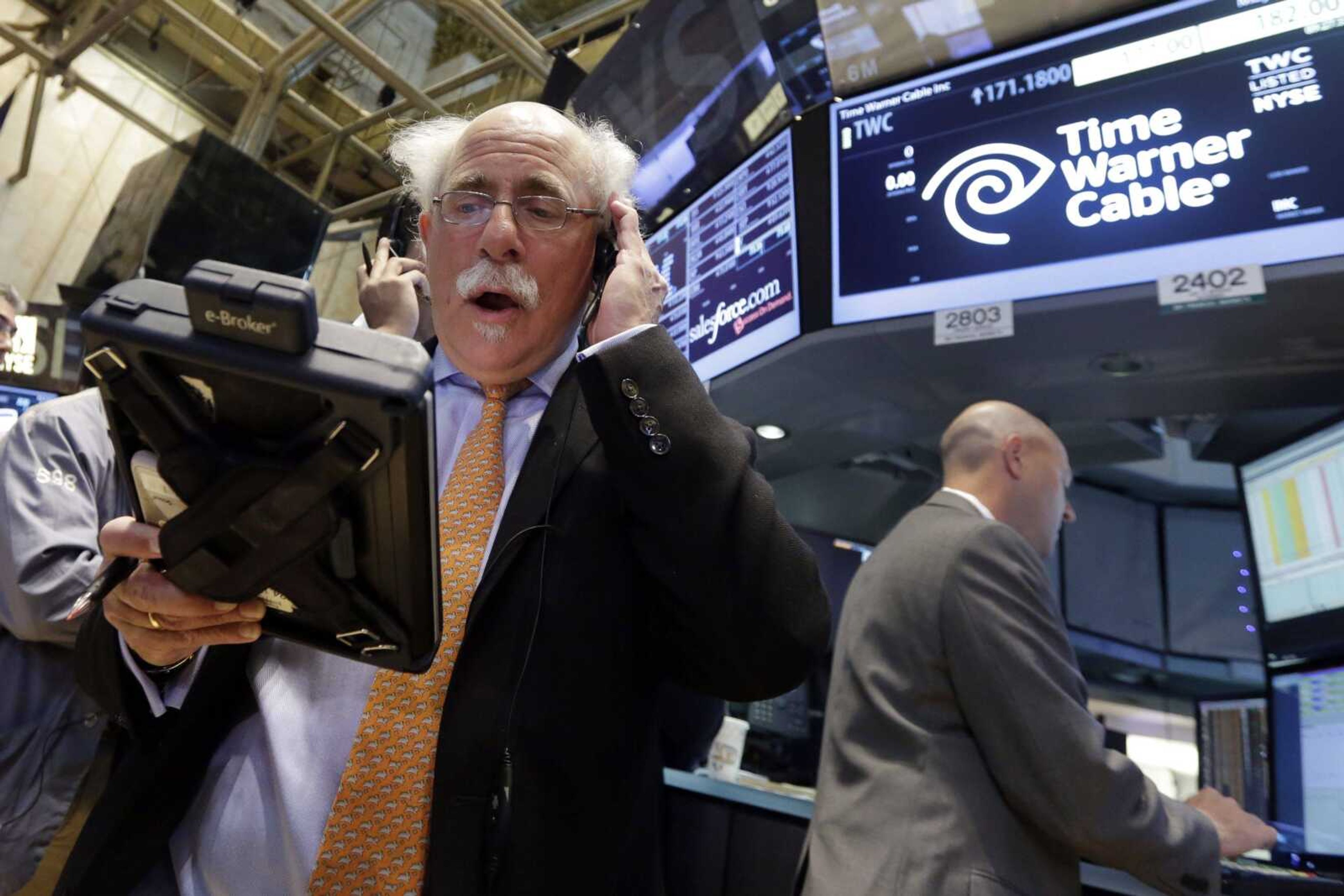 Trader Peter Tuchman, left, works the post Tuesday that handles Time Warner Cable on the floor of the New York Stock Exchange. Charter Communications is buying Time Warner Cable for $55.33 billion, creating another U.S. TV and Internet giant. (Richard Drew ~ Associated Press)