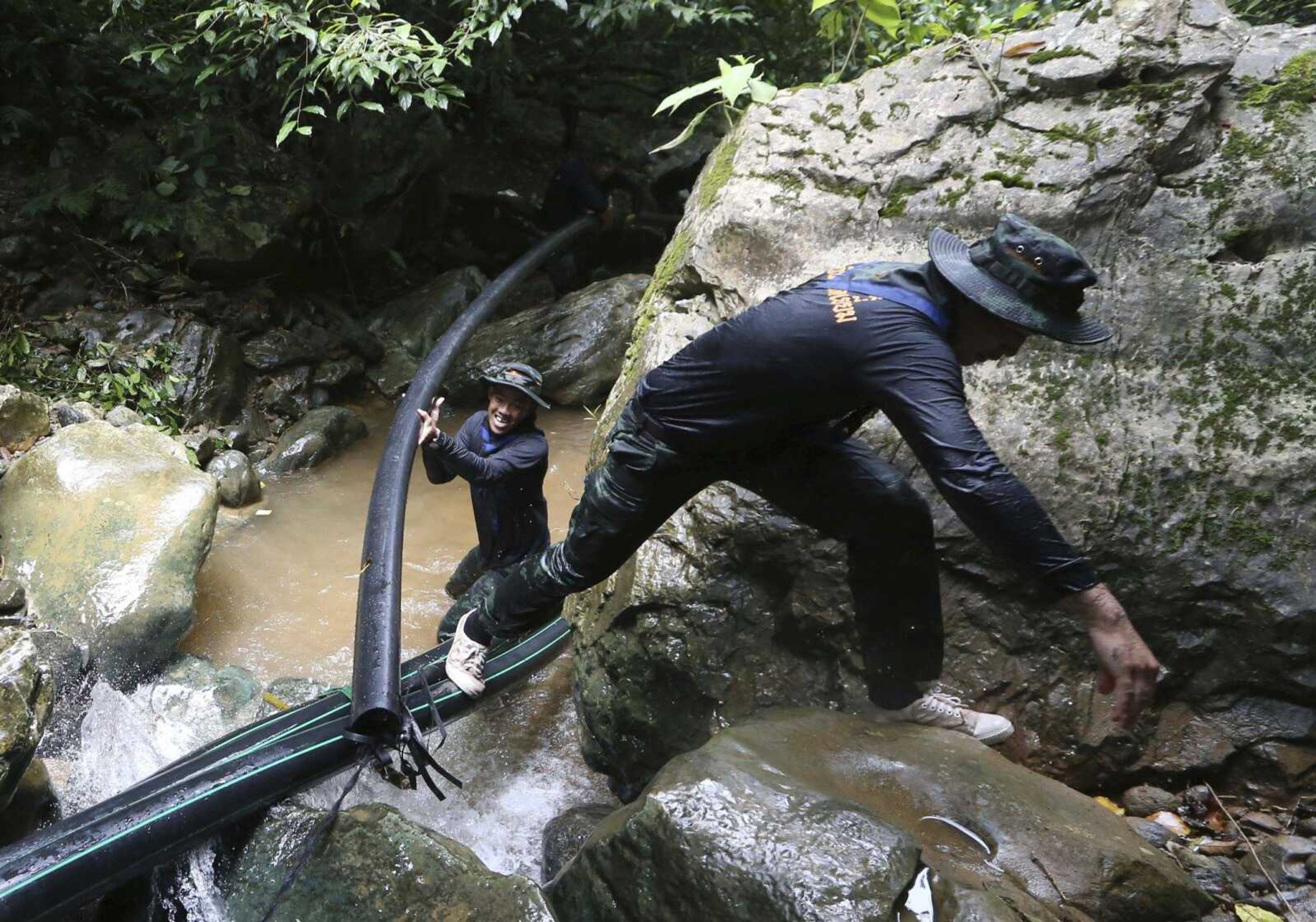 Thai soldiers drag a water pipe Saturday to bypass water from entering a cave where 12 boys and their soccer coach have been trapped since June 23, in Mae Sai, Chiang Rai province, in northern Thailand.