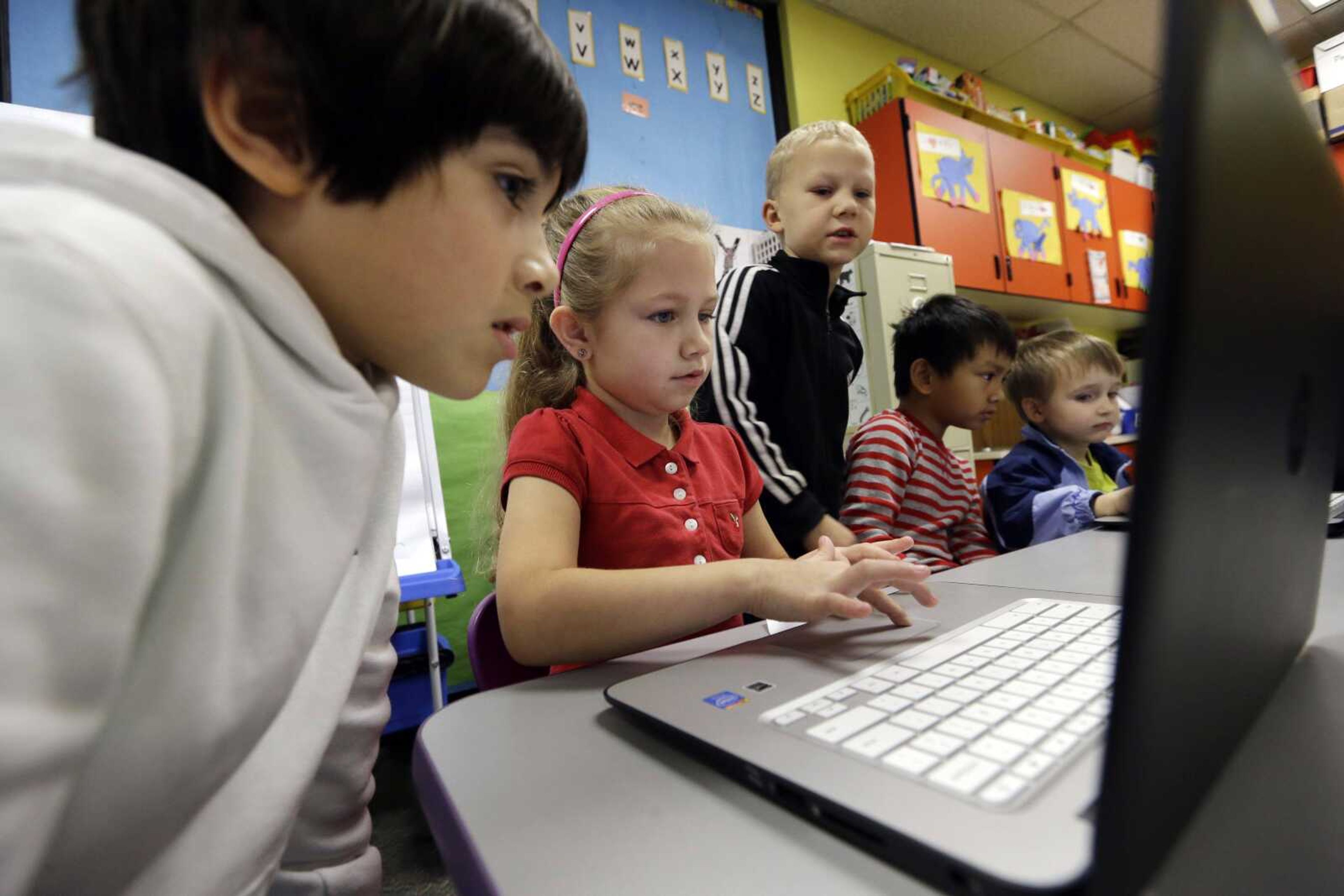 Kindergartner Lauren Meek, second left, works with a pair of second graders as they work on programming during their weekly computer science lesson Nov. 4 at Marshall Elementary School in Marysville, Washington. (AP Photo/Elaine Thompson)