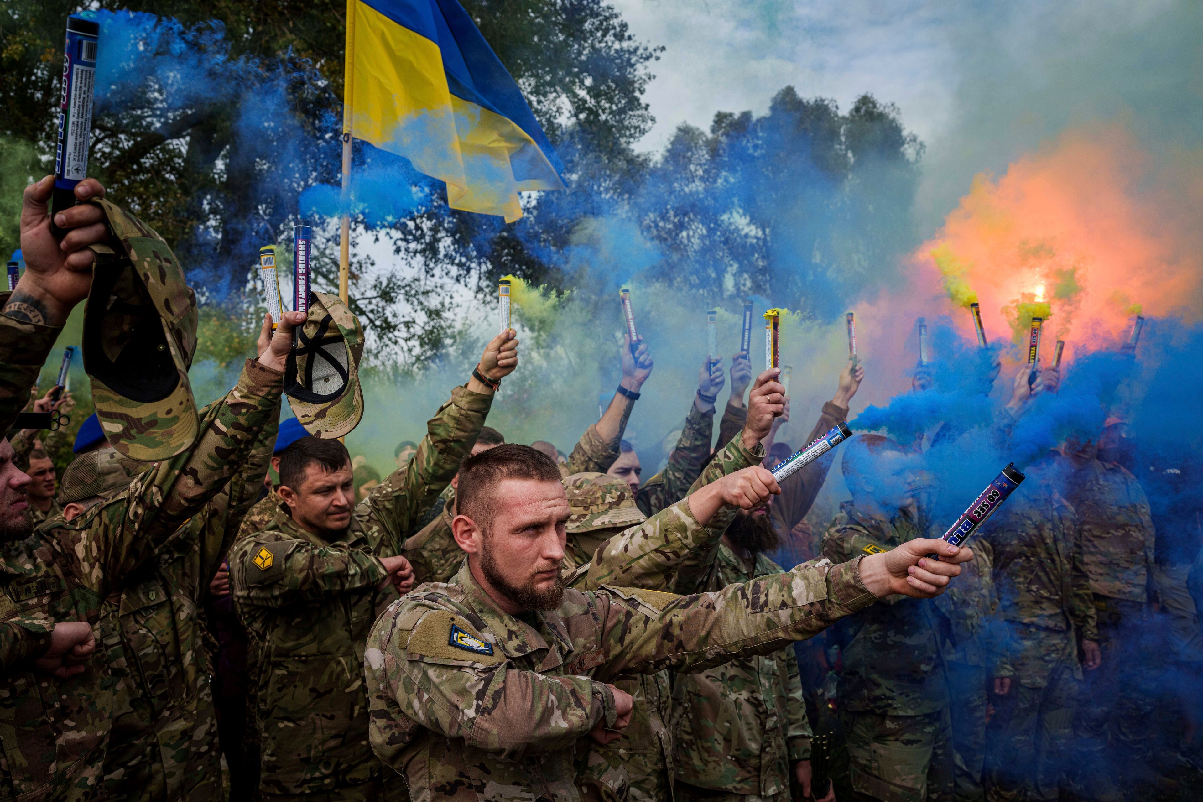 Ukrainian servicemen of the Azov brigade light flares during the funeral ceremony of fallen comrade Ihor Kusochek, in Travkine, Chernihiv region, Ukraine, Friday Oct. 4, 2024. (AP Photo/Evgeniy Maloletka)