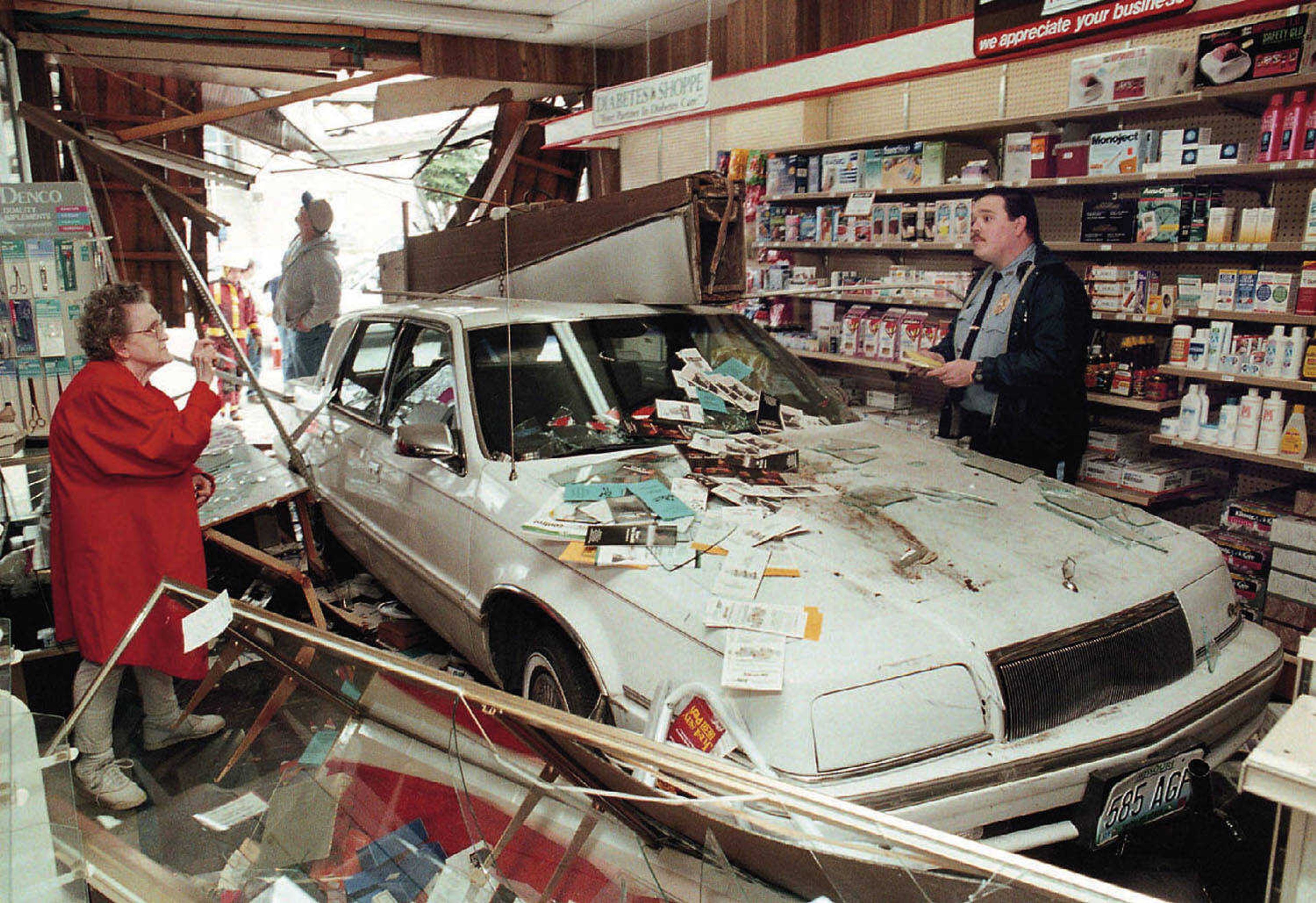 Virginia Bollinger, left, of Jackson, Mo. asks Jackson Police Officer Rick Whitaker about her personal belongings in her car which crashed through the front window and into Jones Drug Store in Jackson, Mo. on Tuesday, February 3, 1998. Her husband, Paul Bollinger, normally waits outside the drug store while his wife goes inside to do business, but this time he came in with her, although in their car. While parking the car, his foot slipped off the brake and onto the gas pedal. No one was injured. (AP Photo, Southeast Missourian, Fred Lynch)