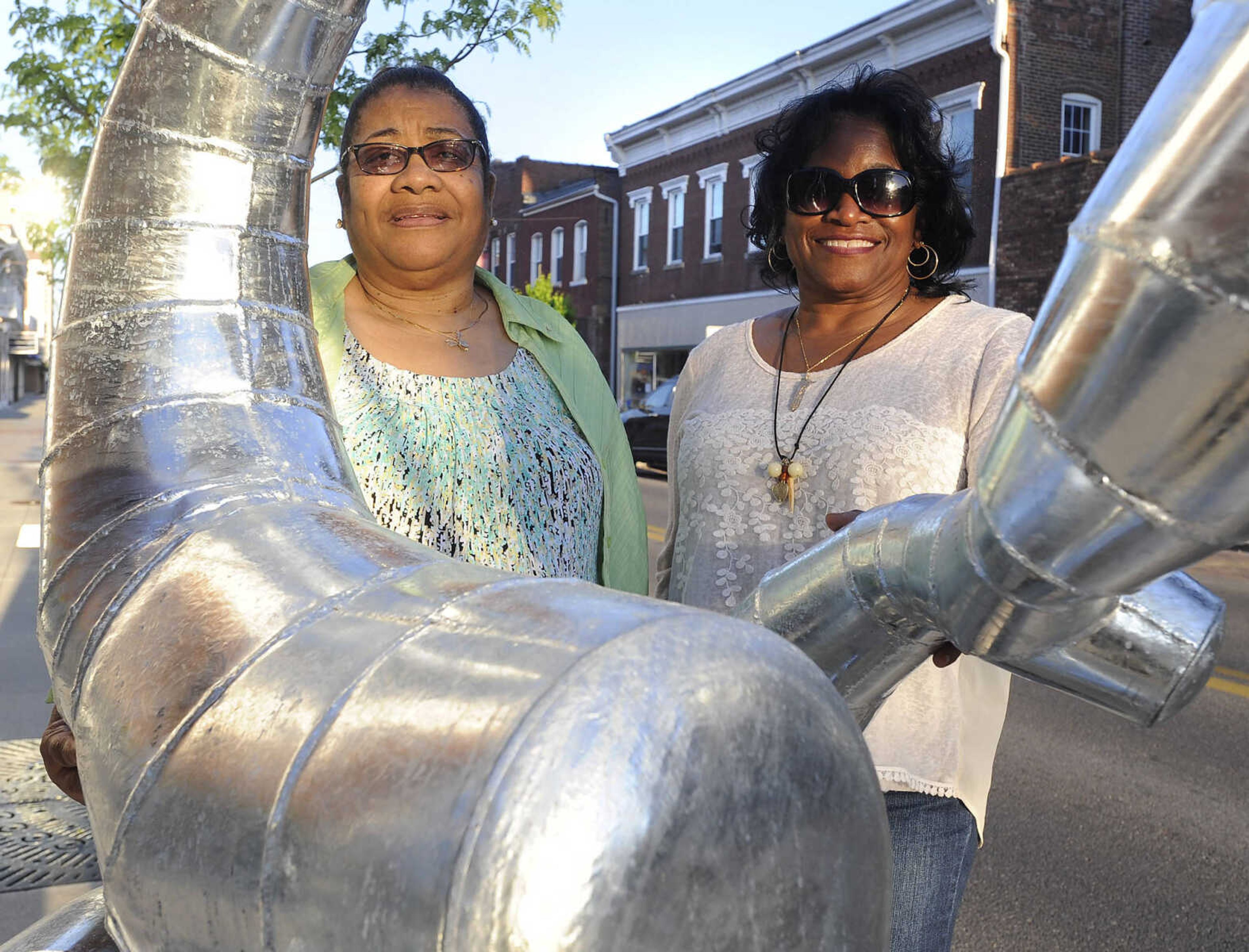 Flora Clemons, left, and Brenda Newbern pose for a photo with a sculpture, "Borborygmid 6," Friday, April 15, 2016 at Broadway and Frederick Street in Cape Girardeau.