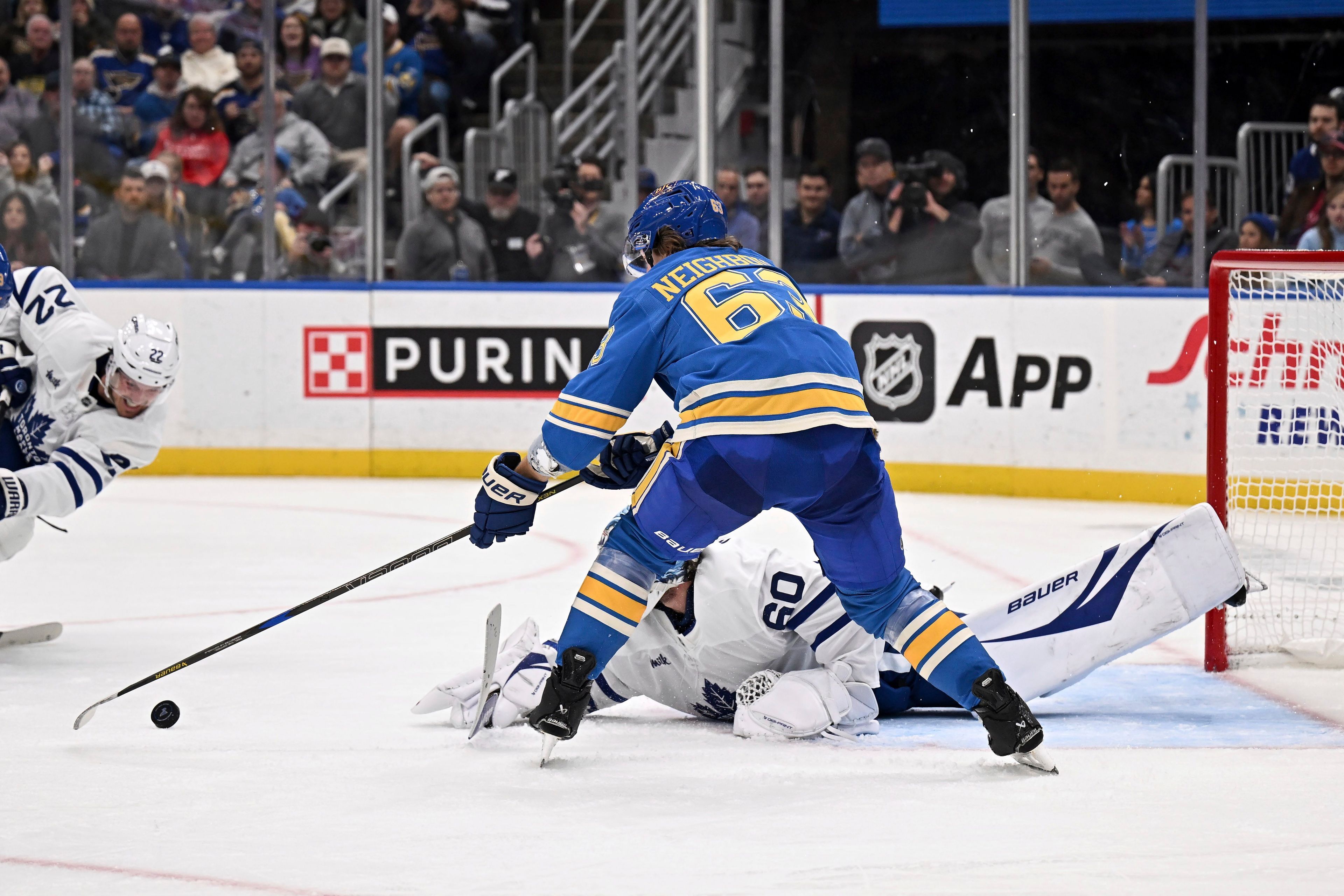 St. Louis Blues' Jake Neighbours (63) reaches for the puck as Toronto Maple Leafs' goaltender Joseph Woll (60) lies on the ice during the second period of an NHL hockey game Saturday, Nov. 2, 2024, in St. Louis. (AP Photo/Connor Hamilton)