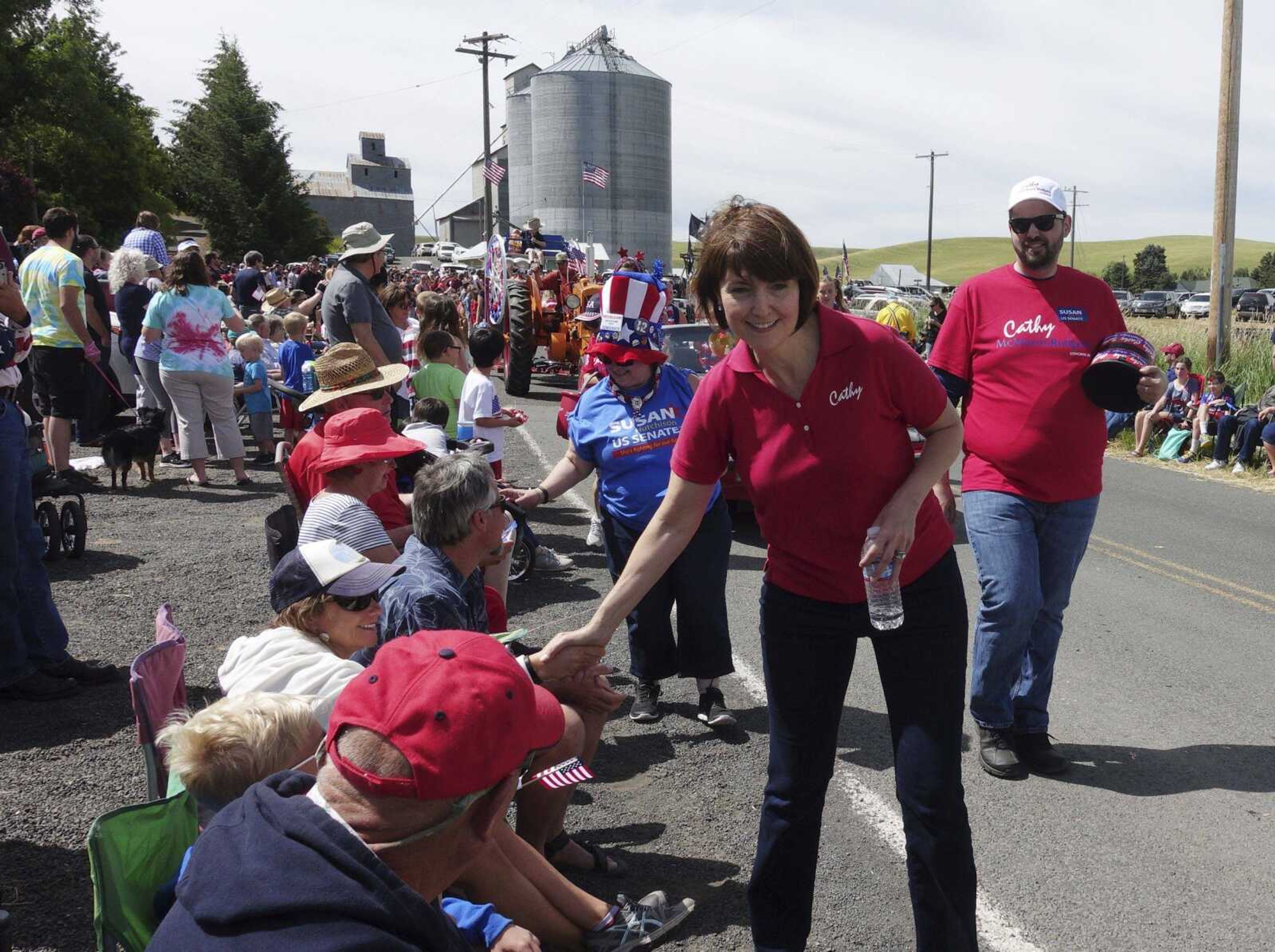 Rep. Cathy McMorris Rodgers, R-Wash., shakes hands as she walks in a Fourth of July parade in Johnson, Washington. Some Democratic candidates are determined not to let Republican members of Congress distance themselves from the president's trade policies.