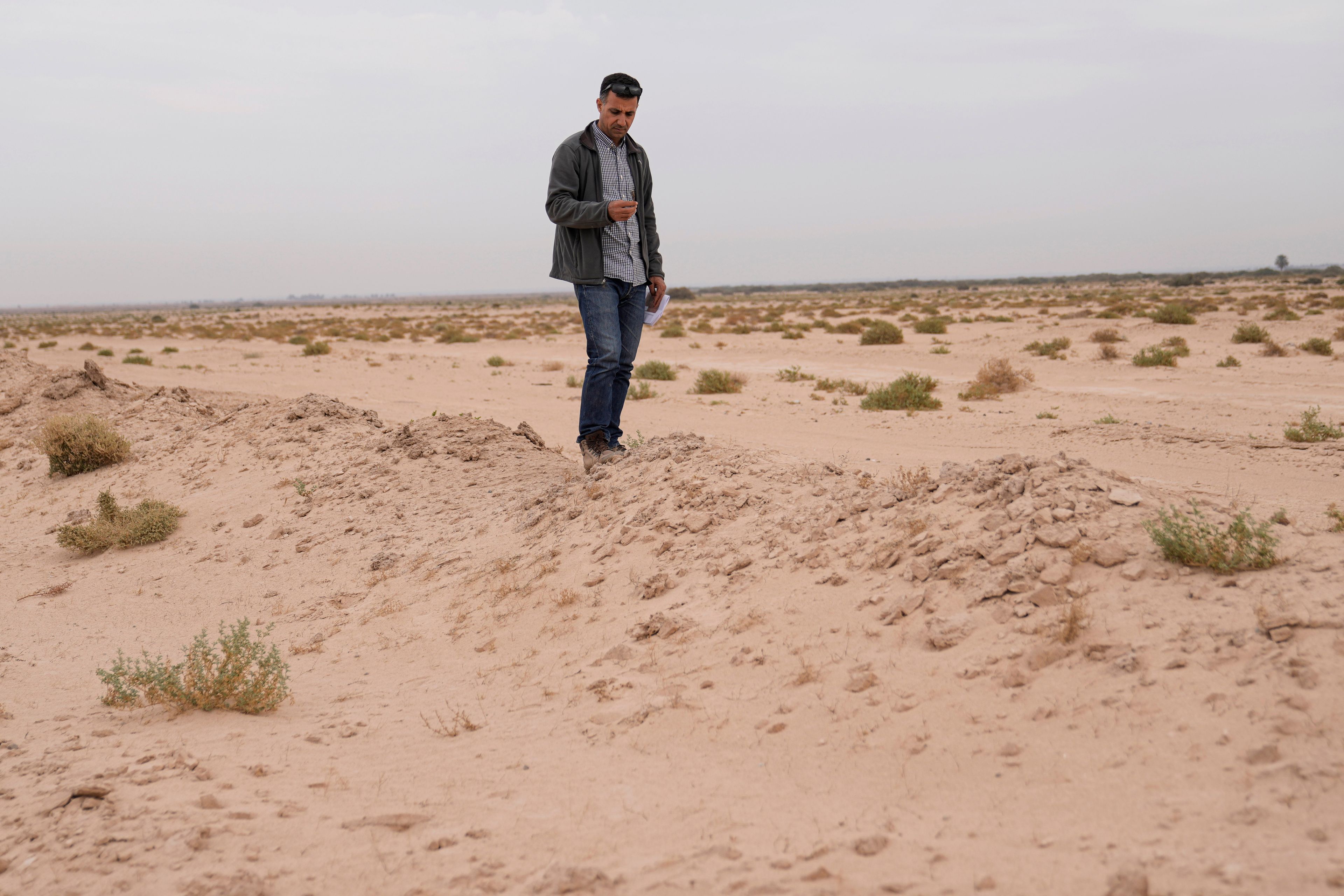 Dr Jaafar al Jotheri holds satellite images and explores the site of the Battle of al-Qadisiyah, which was fought in Mesopotamia - present-day Iraq - in the 630s AD between Arab Muslims and the army of the Sassanid Persian dynasty during a period of Muslim expansion. Abu Sakhir district- southern Najaf, Iraq, Sunday, Nov.10, 2024. (AP Photo/Hadi Mizban)