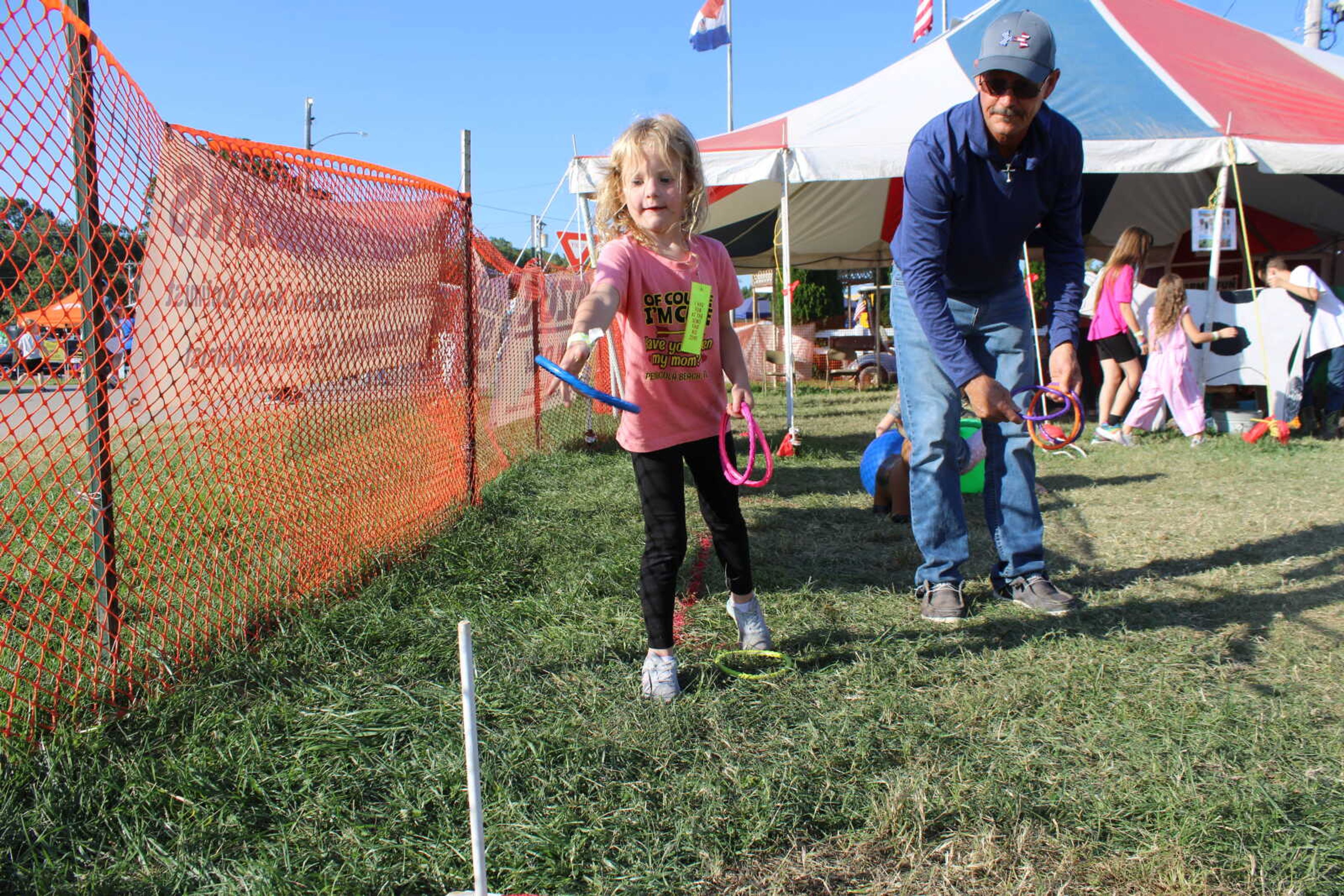 Grandfather Danny Weaver and his granddaughter, Ava Weaver play the ring toss game in the kids area at the SEMO District fair.