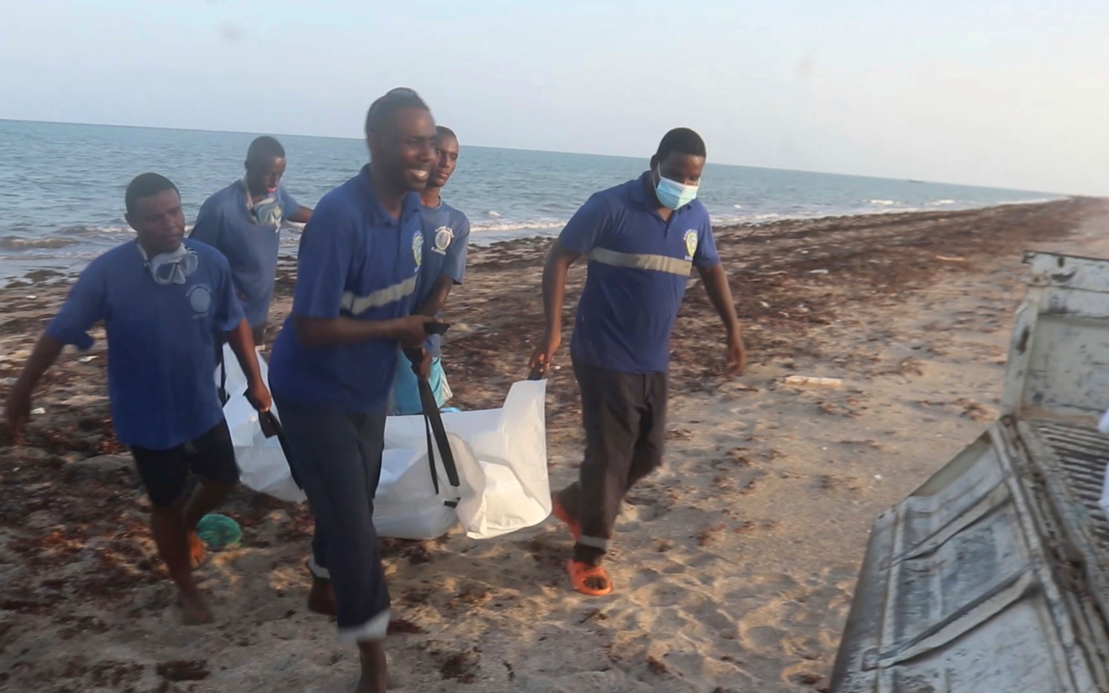 In this image made from video, Djiboutian coast guard workers load bodies of migrants who were washed away on the shore of the Red Sea, off the coast in Djibouti Wednesday, Oct. 2, 2024. (Djiboutian Coast Guard via AP)