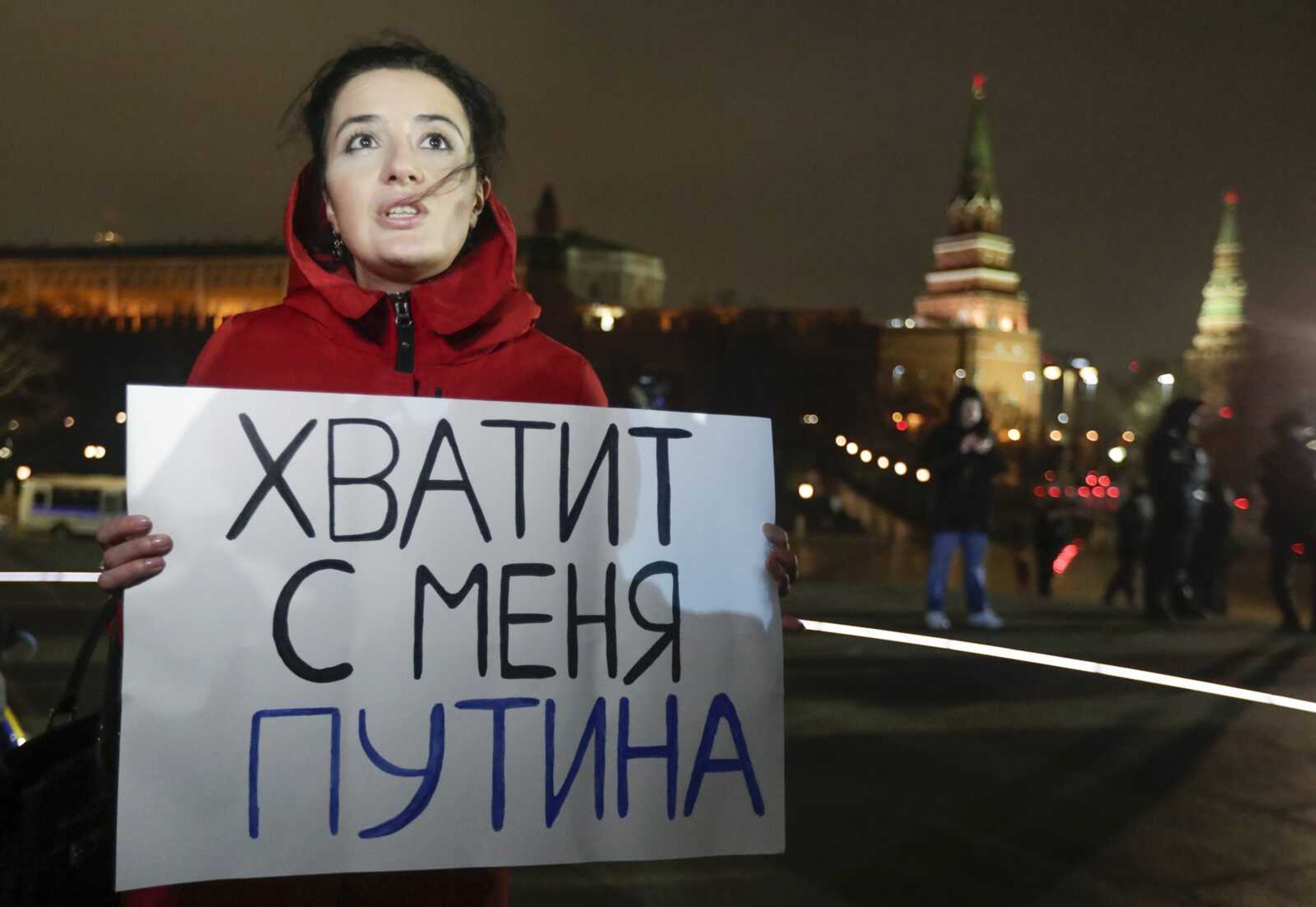 A protester holds a poster that reads: "Enough Putin for me",  in front of the monument of the Prince Vladimir next to the Kremlin in Moscow.