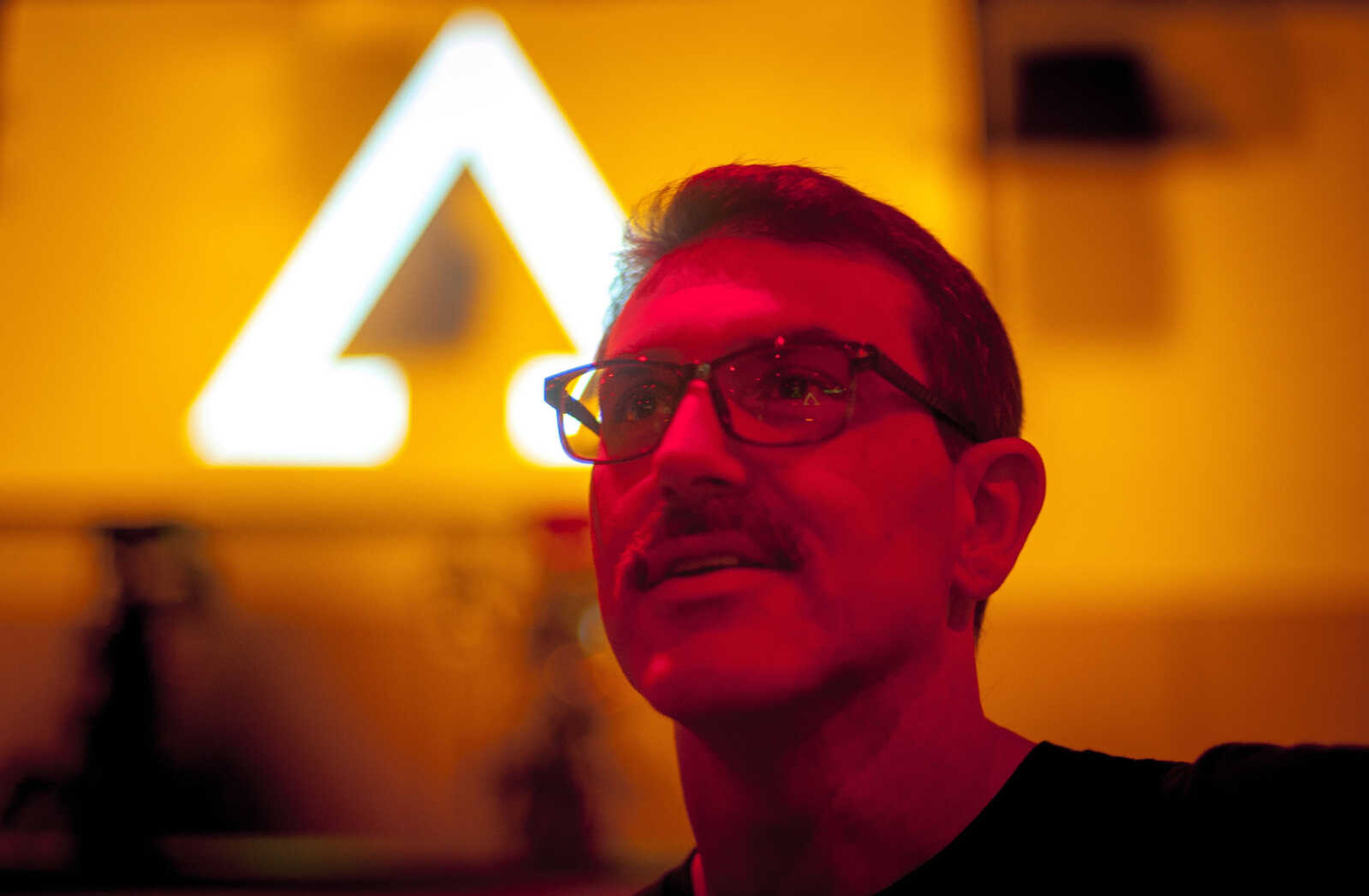 Pastor Chris Vaught is illuminated by colored stage lights in the main worship hall of Connection Point church in Jackson, the logo of which is seen illuminated behind him Thursday, Nov. 21, 2019.