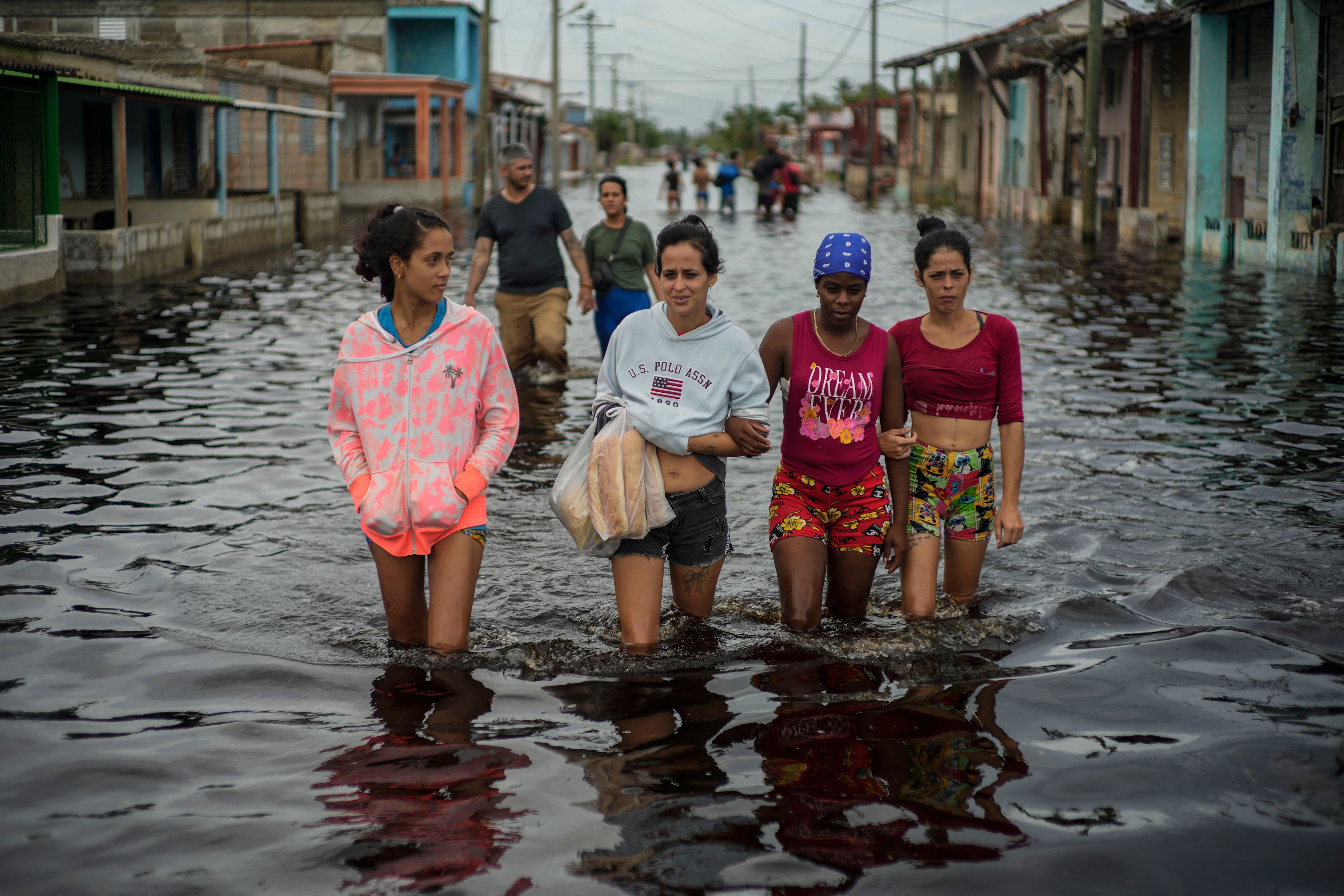 Residents wade through a street flooded in the passing of Hurricane Helene, in Batabano, Mayabeque province, Cuba, Thursday, Sept. 26, 2024. (AP Photo/Ramon Espinosa)