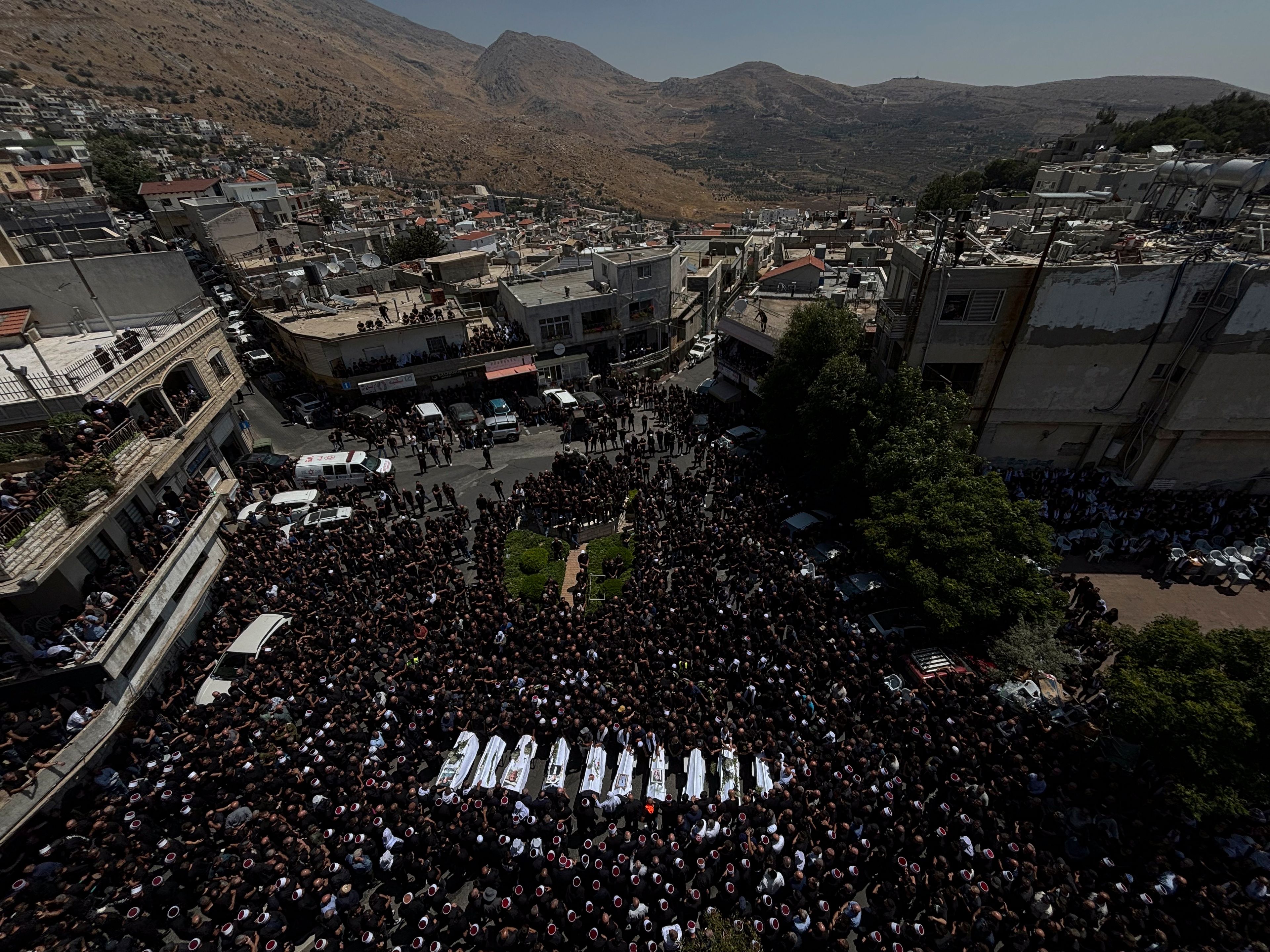 Mourners from the Druze minority surround the bodies of some of the 12 children and teens killed in a rocket strike at a soccer field, during their funeral, in the village of Majdal Shams, in the Israeli-annexed Golan Heights, Sunday, July 28, 2024. It's the deadliest strike on an Israeli target along the country's northern border since the fighting between Israel and the Lebanese militant group Hezbollah began. (AP Photo/Leo Correa)