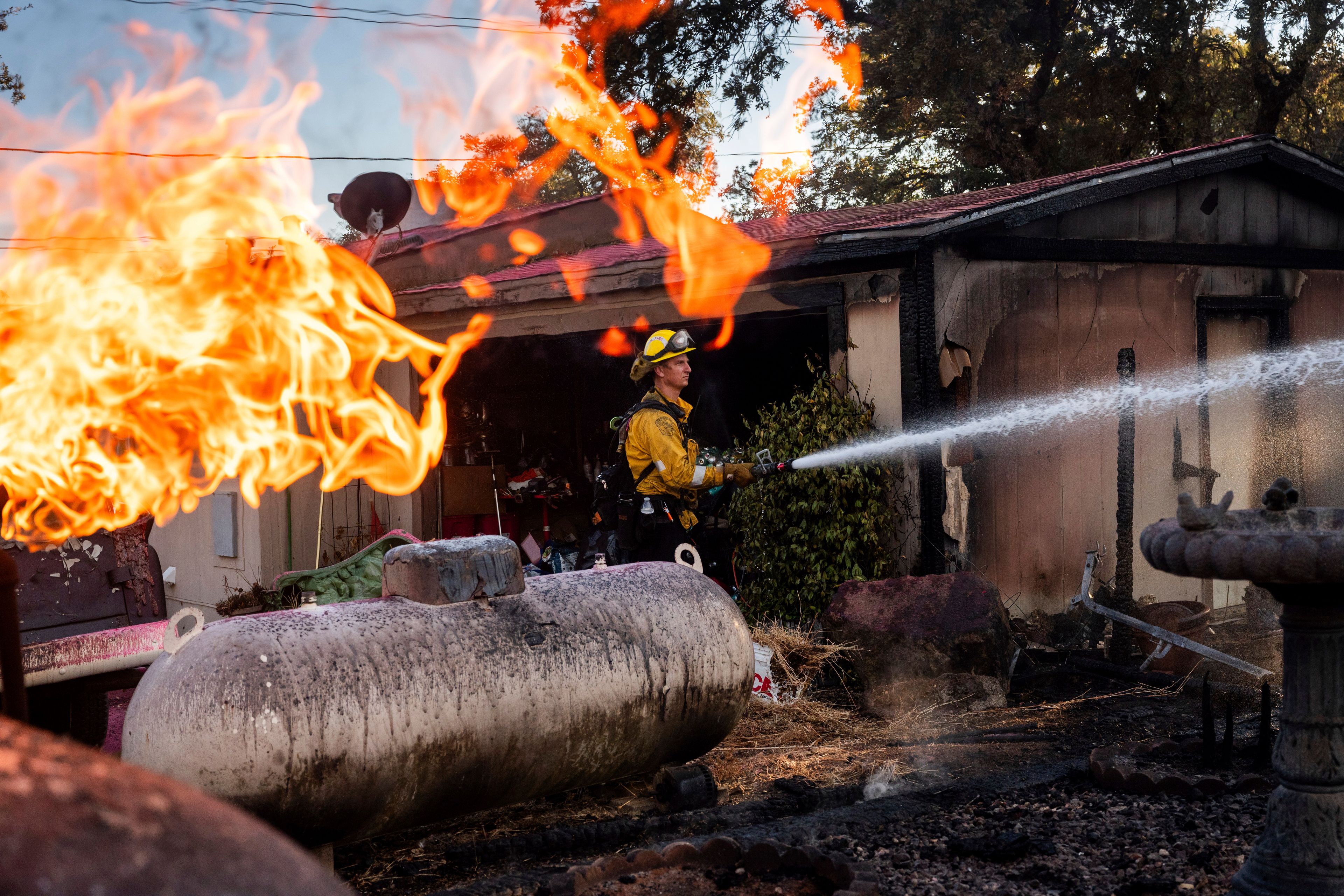 Firefighter Nolan Graham sprays water around a scorched garage as the Boyles fire burns in Clearlake, Calif., on Sunday, Sept. 8, 2024. (AP Photo/Noah Berger)