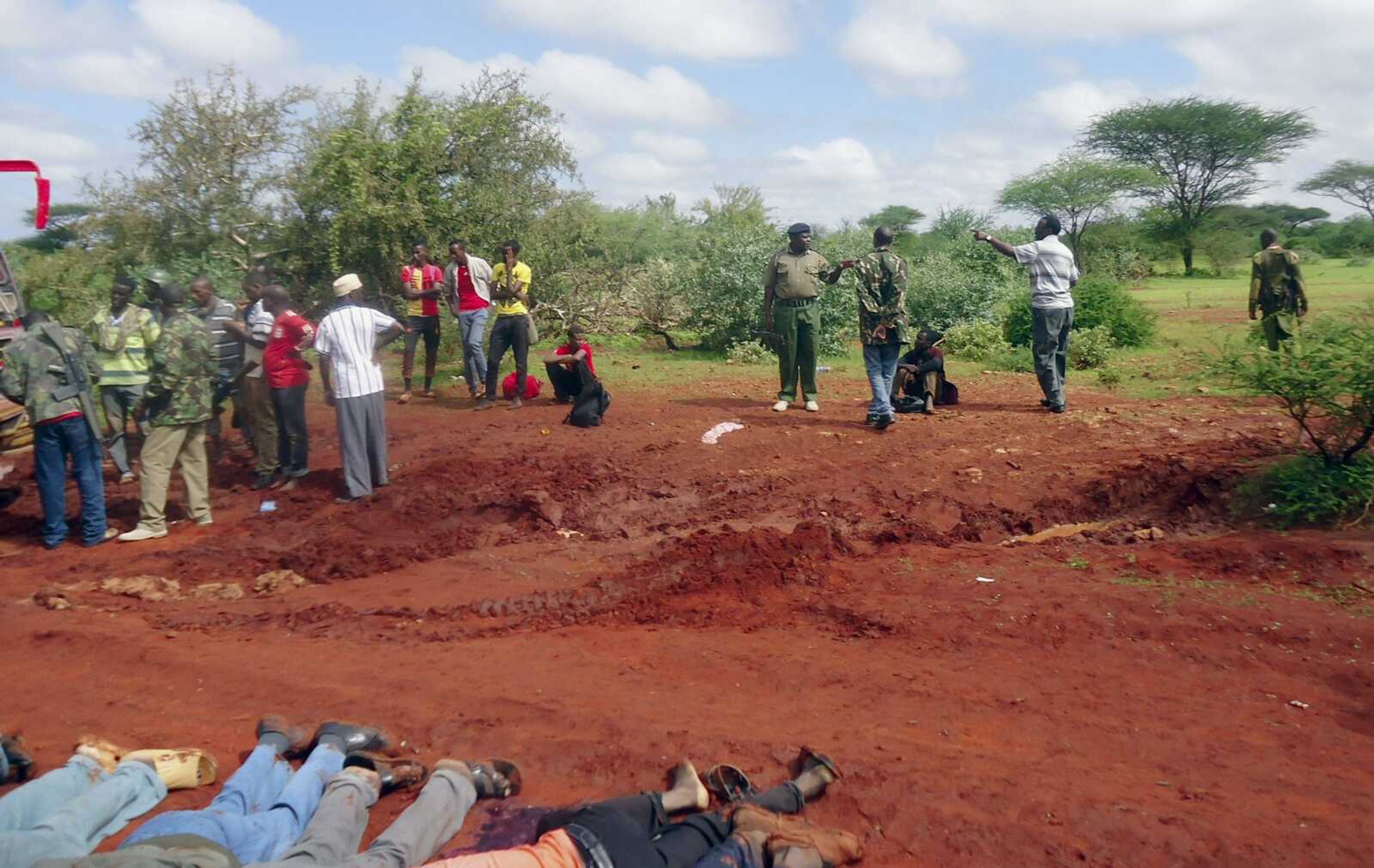 Kenyan security forces examine the scene as bodies of some of the victims lie in a line on the ground at the location of an attack on a bus about 30 miles outside the town of Mandera near the Somali border in northeastern Kenya. (Associated Press)