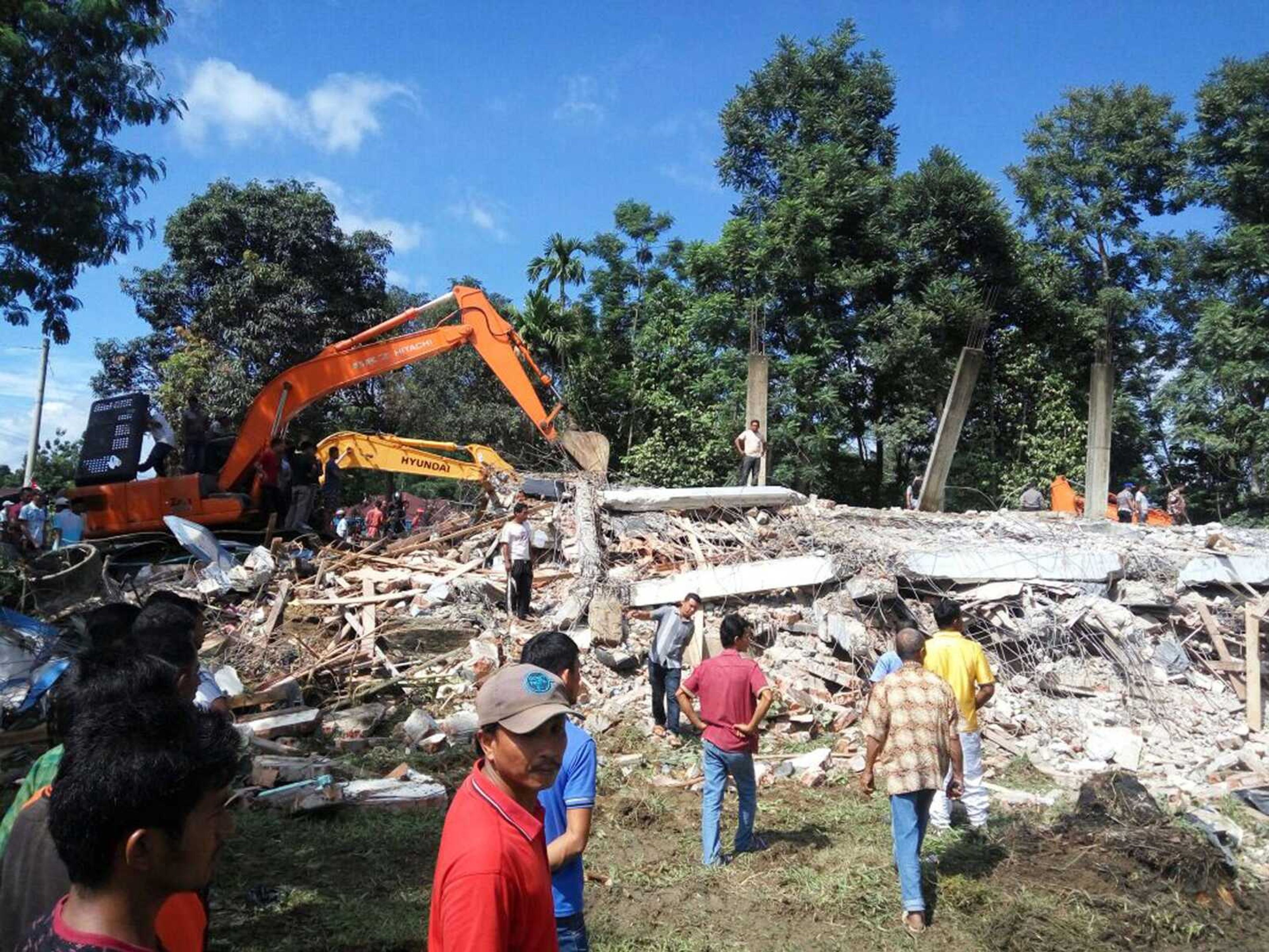 Rescuers use heavy machinery to search for survivors under the rubble of a collapsed building after an earthquake Wednesday in Pidie Jaya, Aceh province, Indonesia.