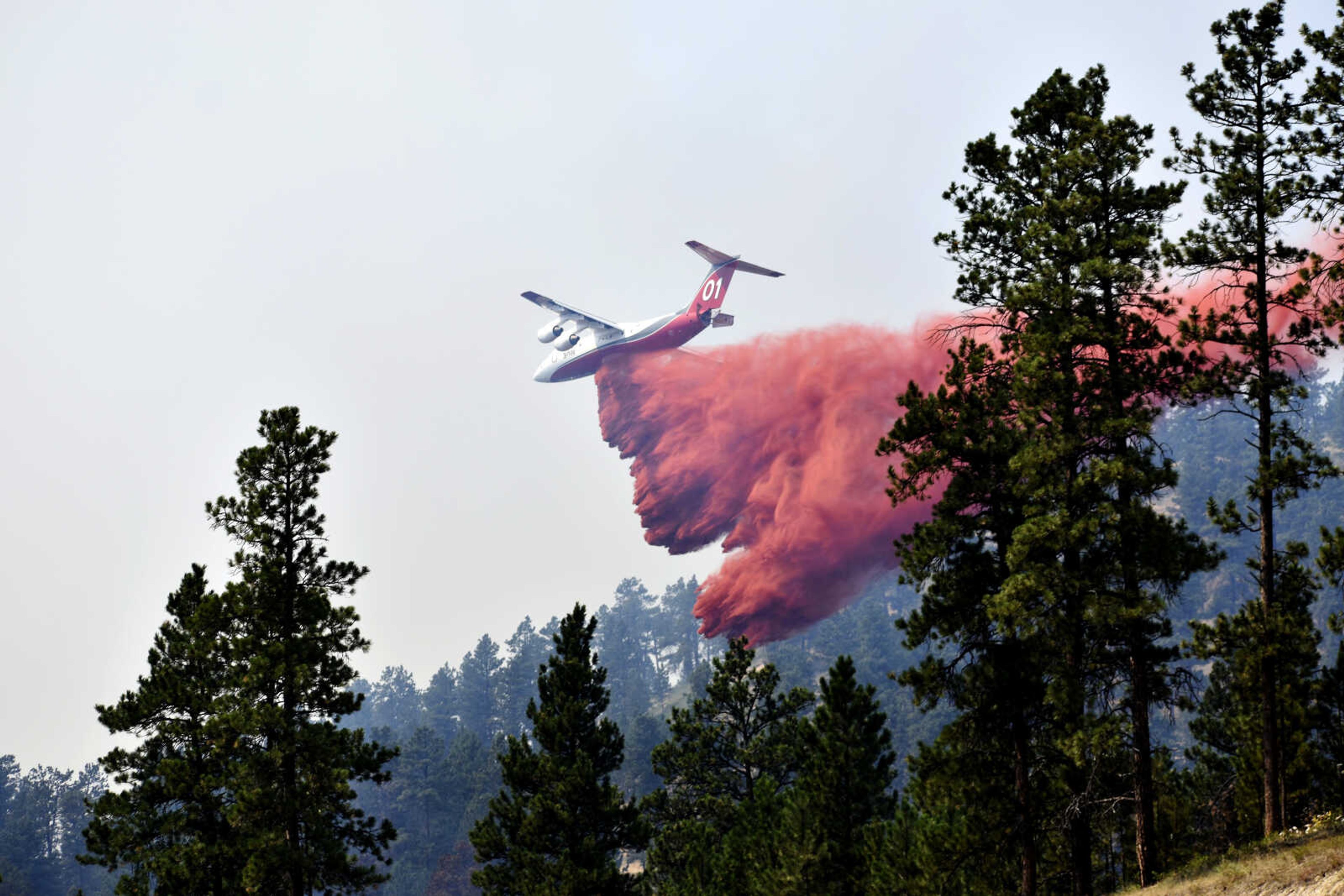 An aircraft drops fire retardant to slow the spread of the Richard Spring fire on Aug. 11, 2021, east of Lame Deer, Montana. A legal dispute in Montana could drastically curb the government's use of aerial fire retardant to combat wildfires. Environmentalists have sued the U.S. Forest Service over waterways being polluted with the potentially toxic red slurry that's dropped from aircraft. Forest Service officials have acknowledged more than 200 cases of retardant landing in water.