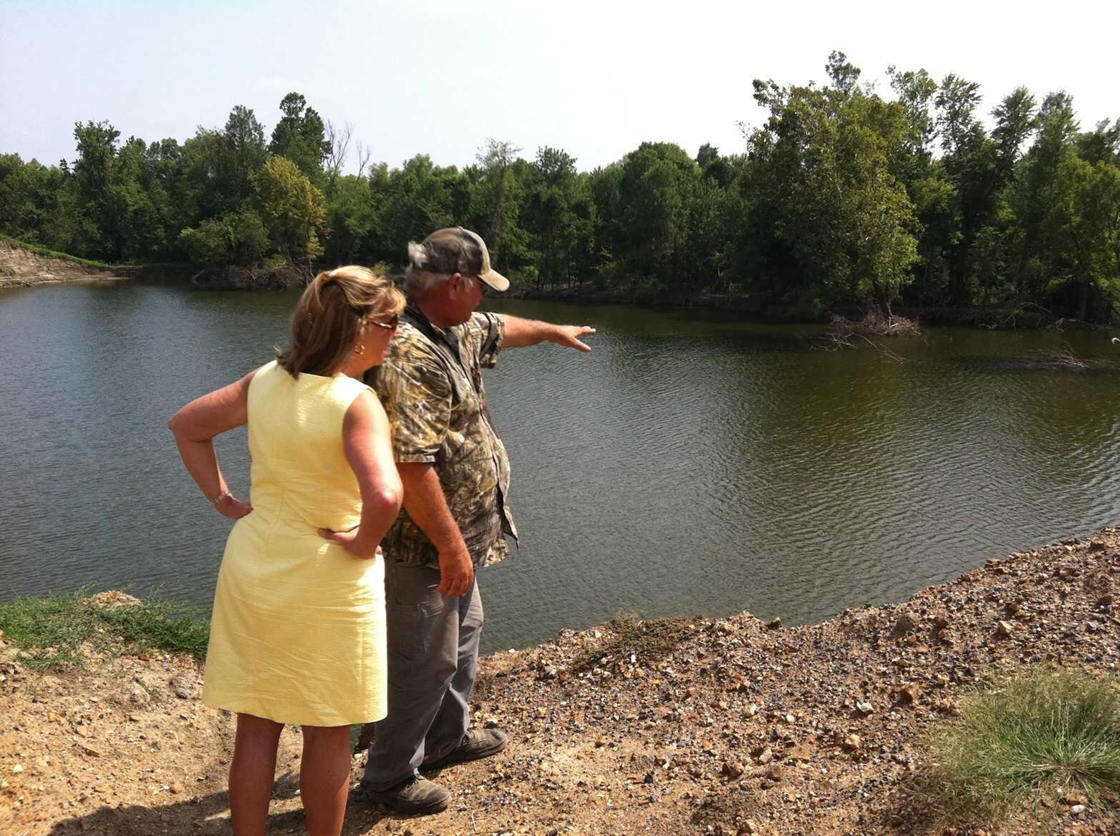 Milus Gary Wallace, right, shows Rep. Jo Ann Emerson a 50-foot-deep hole created by the third and final breach of the Mississippi River levee, near County Road 520. In the area surrounding the hole, sand deposits seven to eight feet deep prevent crops from being planted. Wallace said he has planted crops on about a third of his land; the rest is either underwater or covered in sand. (Melissa Miller)