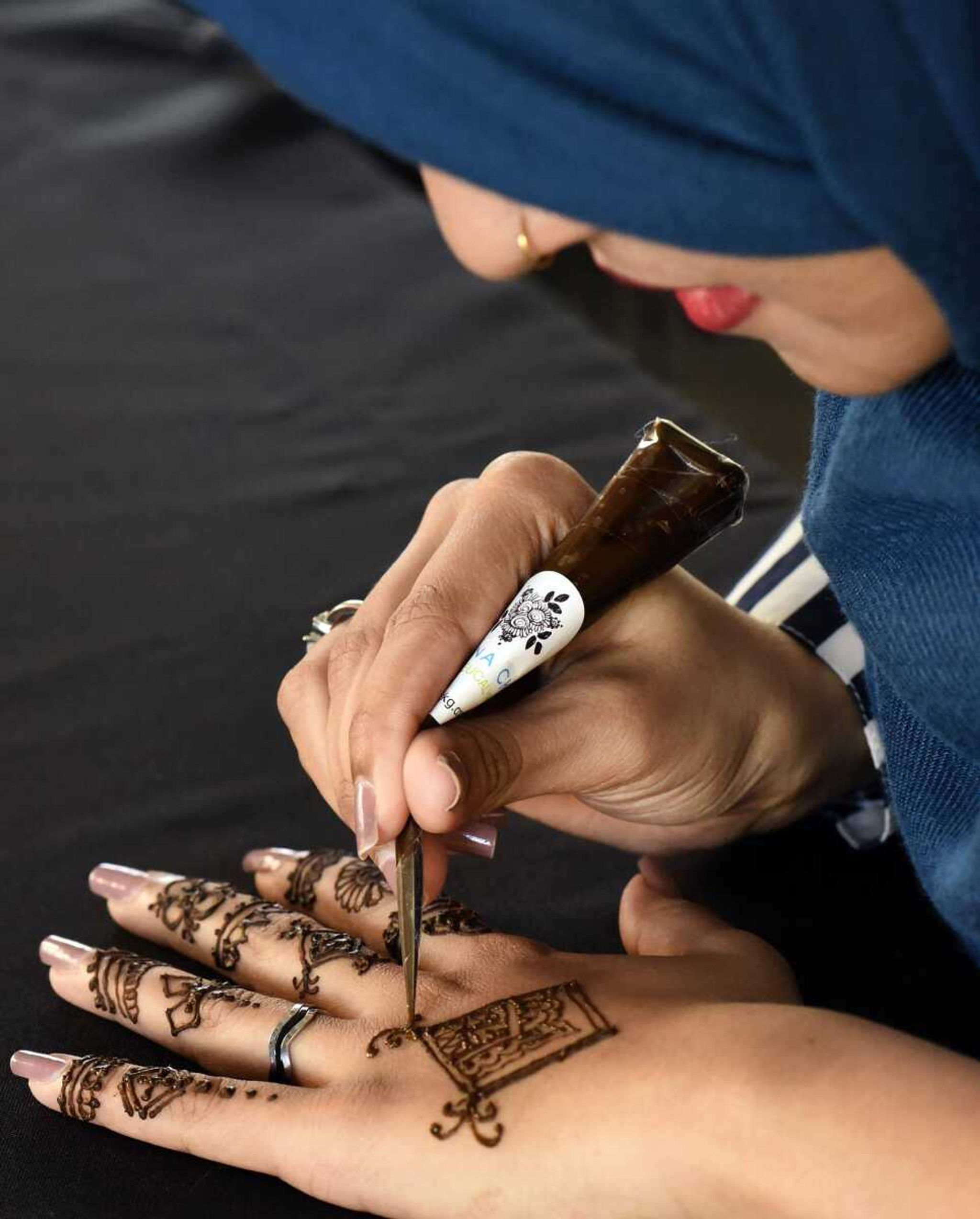 Iffat Ara free-hands a henna design onto her left hand on  March 10.