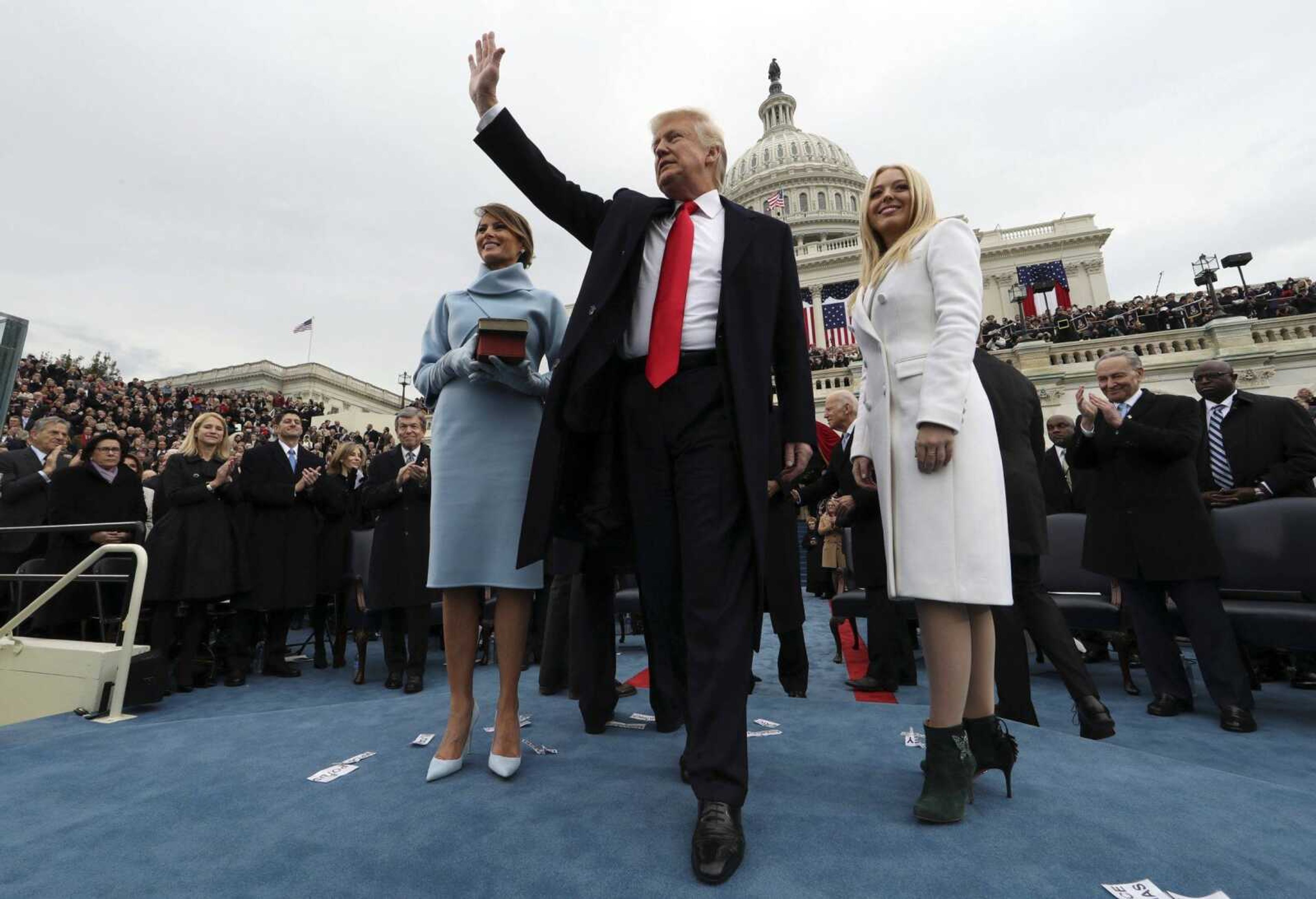 President Donald Trump waves after taking the oath of office as his wife, Melania, holds the Bible and daughter Tiffany Trump looks out to the crowd during the swearing-in ceremony Friday on Capitol Hill in Washington.