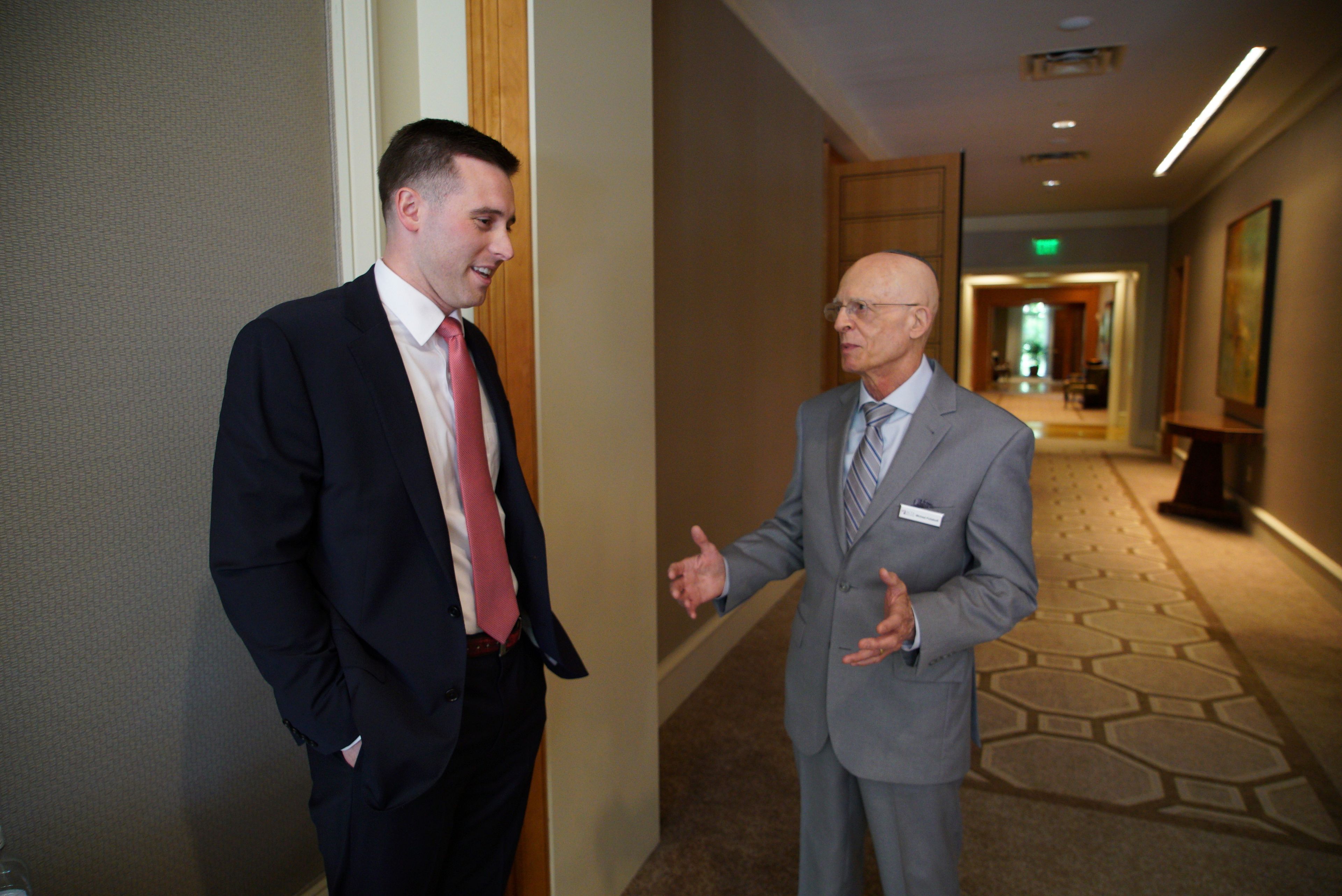 U.S. Marine Capt. Jameson Broggi, left, speaks with Michael Poliakoff, CEO of the American Council of Trustees and Alumni, before a luncheon in Cary, N.C., on Monday, April 29, 2024. With help from ACTA, Broggi has written legislation in two states to require public college students to take a civics class in order to graduate. (AP Photo/Allen G. Breed)