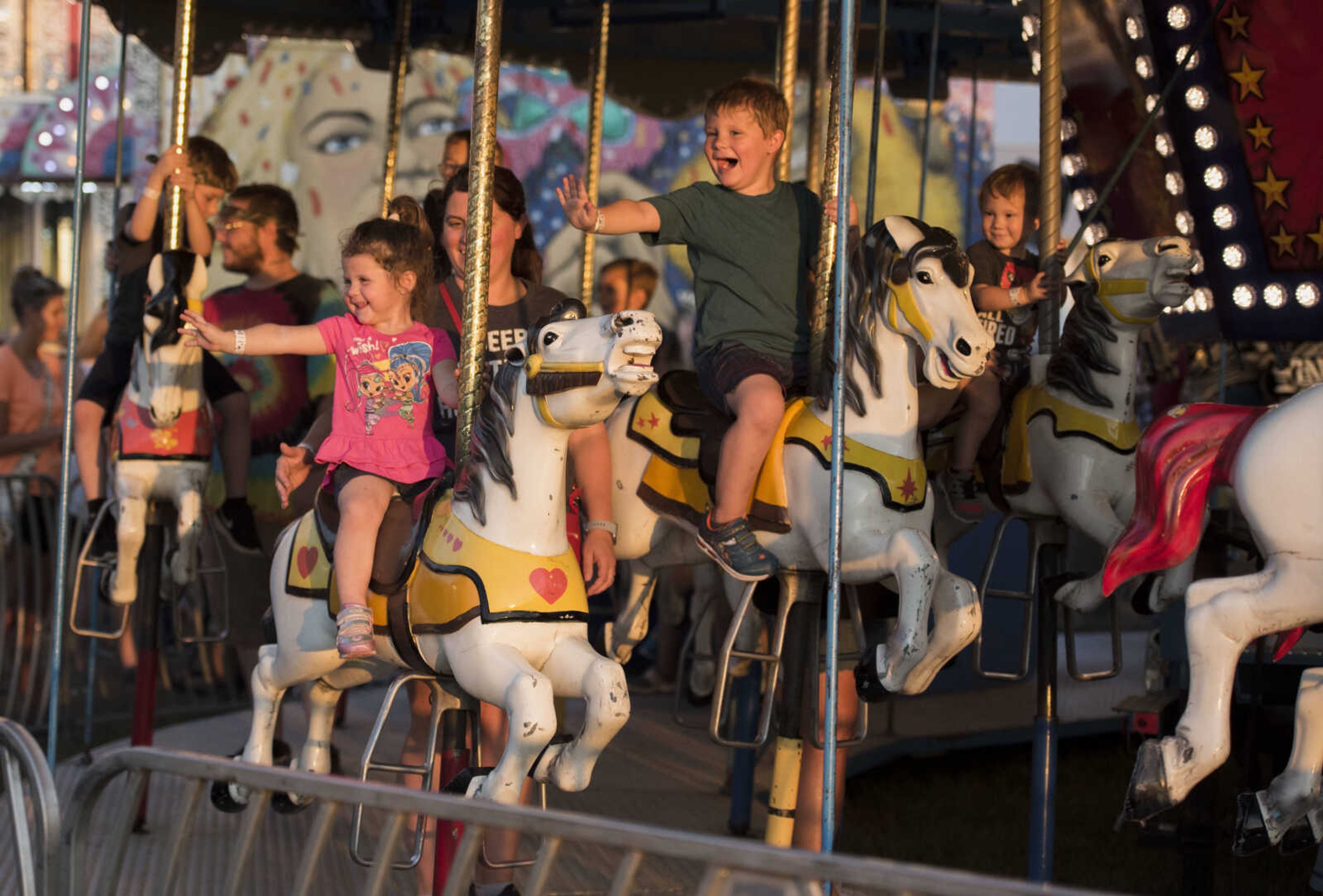 Landry Smith, 2, center left, sits next to her cousin Keaton Carver, 3, as they ride the carousel with Krystle Smith on Tuesday, Sept. 10, 2019, during the SEMO District Fair at Arena Park in Cape Girardeau.