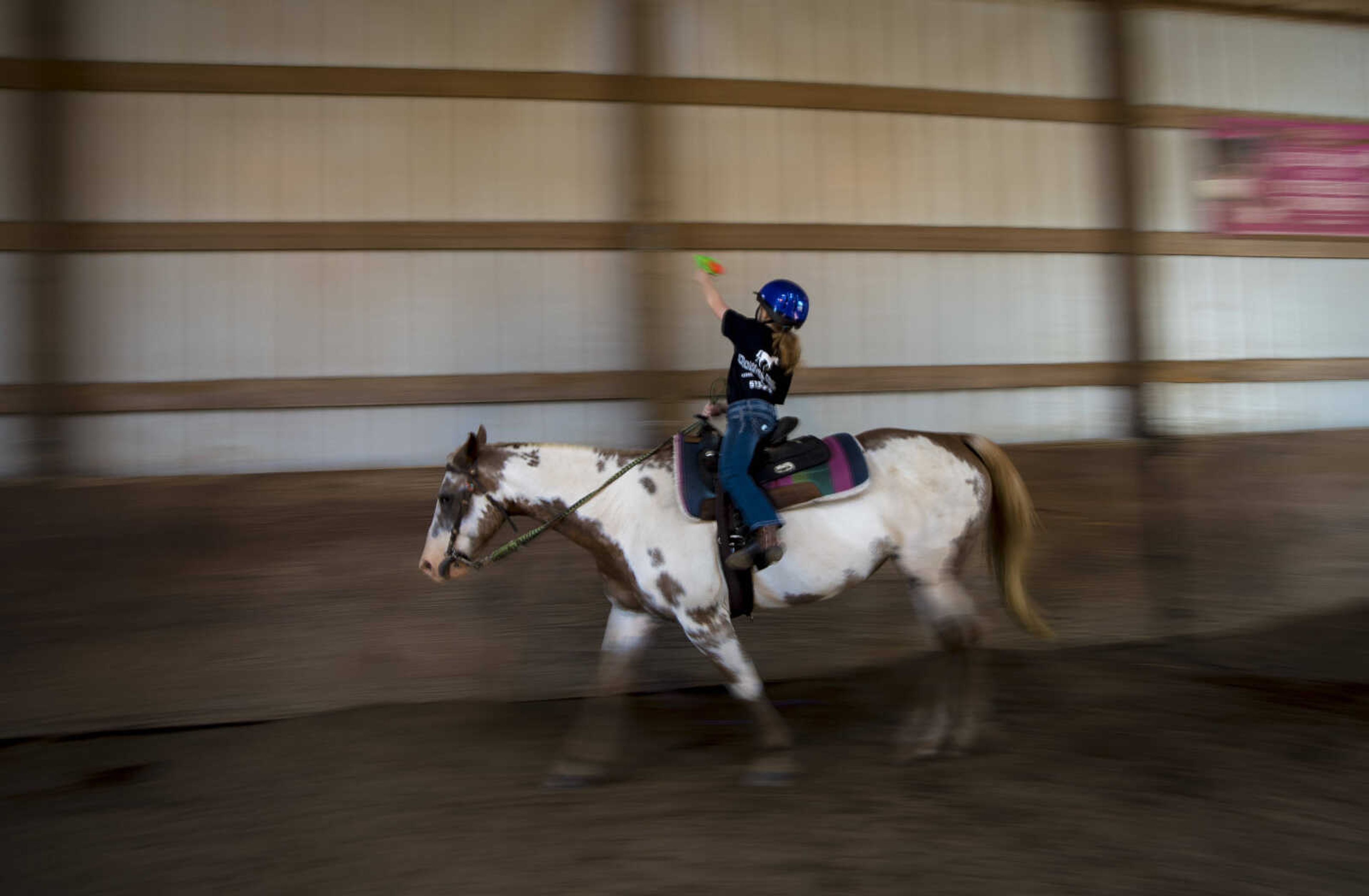 Payton Lynch, 6, holds up her squirt gun to shoot at a target as practice called cowboy mounted shooting while she rides during the Rolling Hills Youth Day Camp Wednesday, June 7, 2017 in Cape Girardeau.