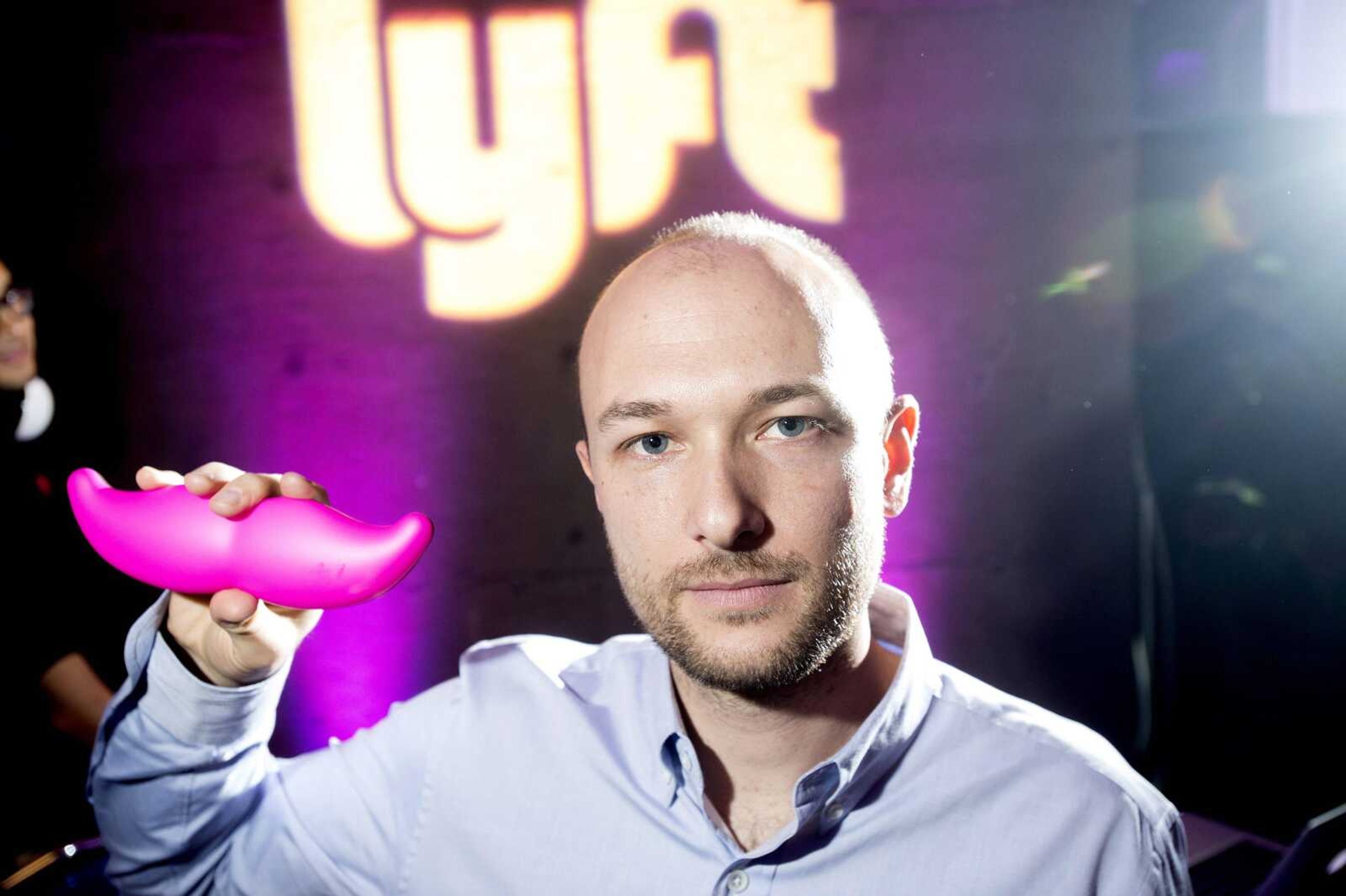 Logan Green, co-founder and CEO of Lyft, displays his company's "glowstache" during a launch event in San Francisco. On Monday, General Motors Co. announced it is investing $500 million in ride-sharing company Lyft Inc. to speed the development of on-demand, self-driving cars. (Noah Berger ~ Associated Press)