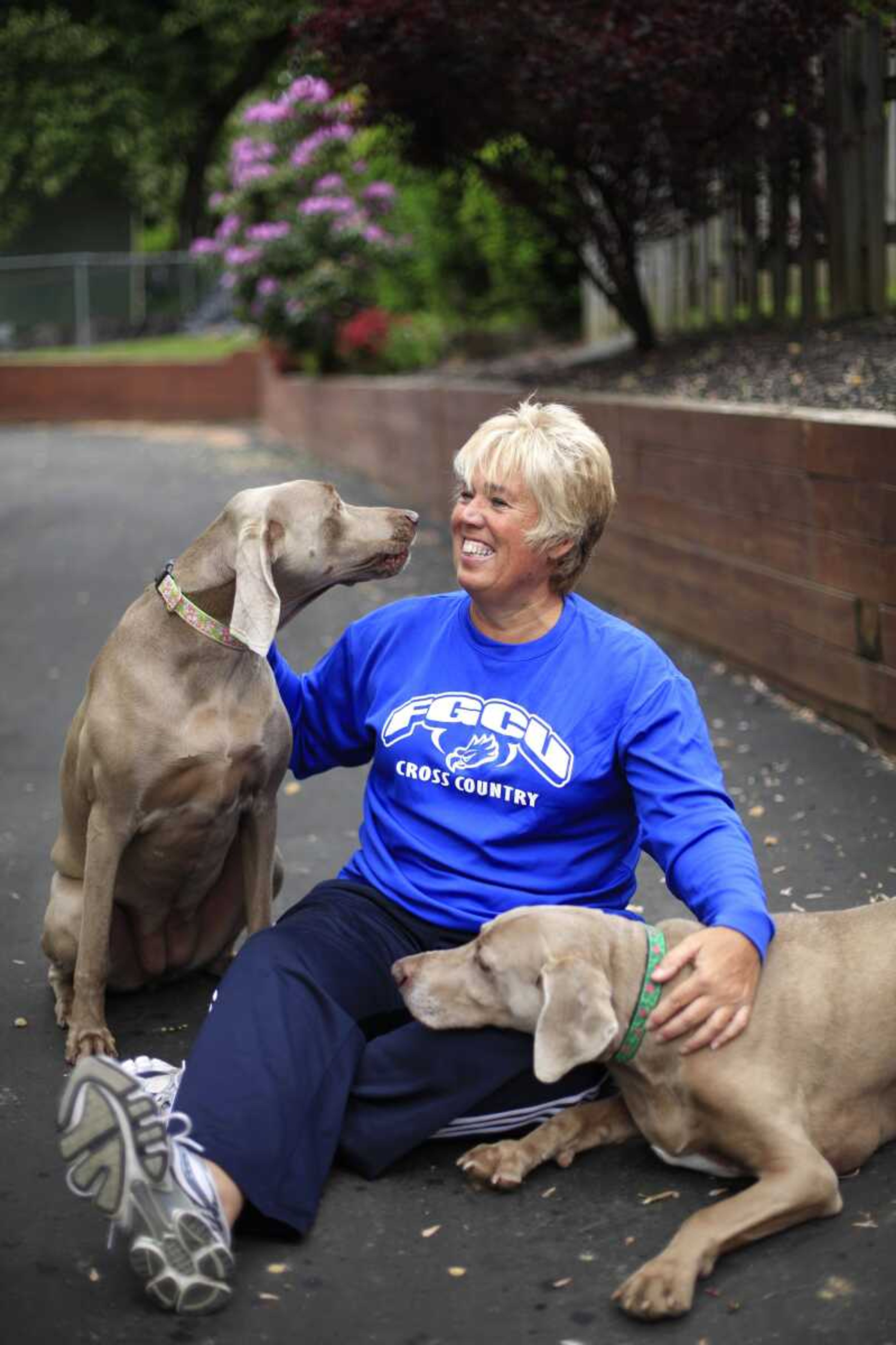 Karen Cornwall plays with her dogs Bel, left, and Mac, in front of her home in Havertown Pa. Cornwall, a nurse who played a slew of sports since childhood, had both knees replaced last year when she was 54. (AP Photo/Matt Rourke)