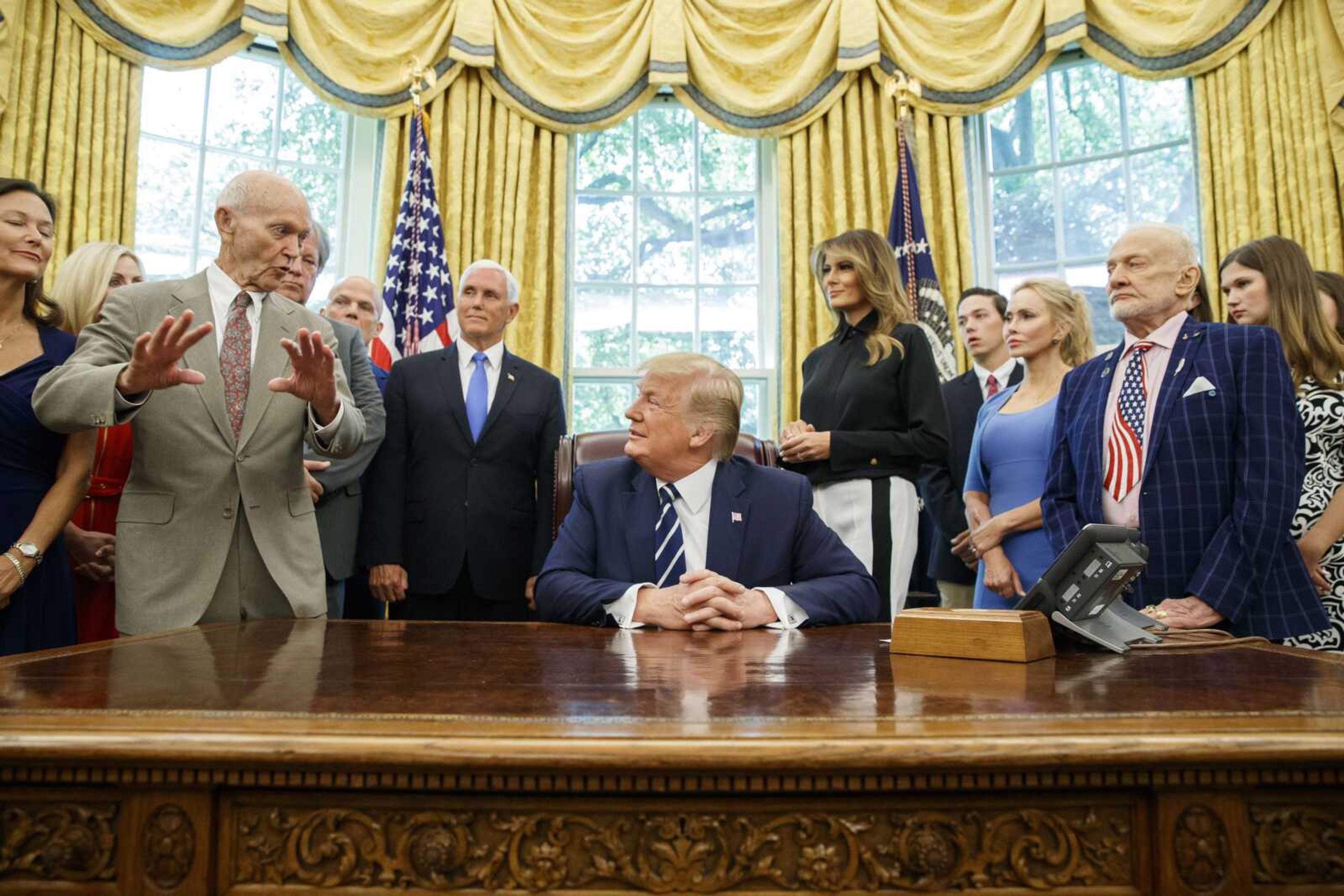 President Donald Trump, center, listens to Apollo 11 astronaut Michael Collins, left, accompanied by Buzz Aldrin, Vice President Mike Pence and first lady Melania Trump, during a photo opportunity commemorating the 50th anniversary of the Apollo 11 moon landing, Friday in the Oval Office of the White House in Washington.