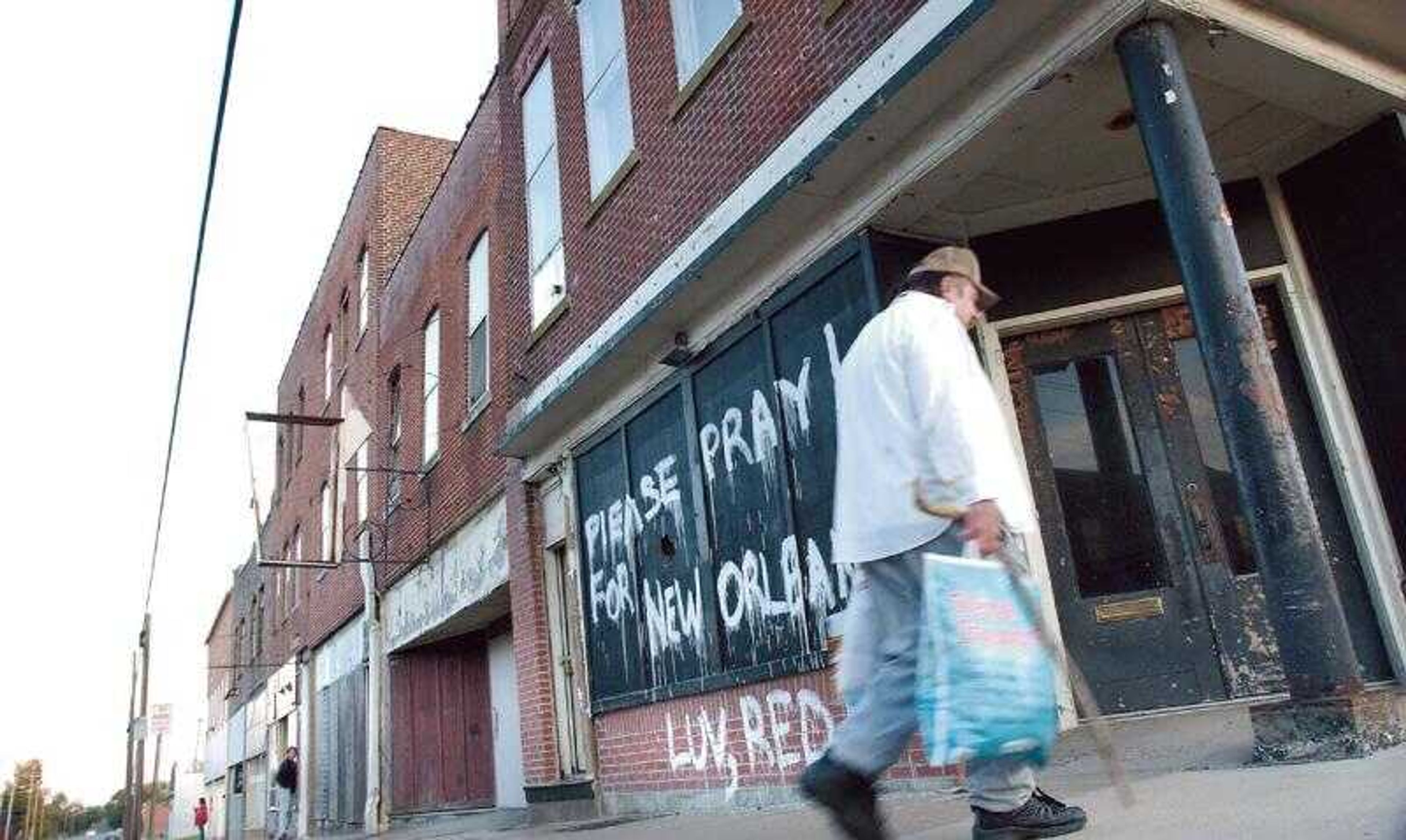 Zachary Glueck carried grocery bags past some run-down buildings at the corner of Sprigg and Good Hope streets Friday. (FRED LYNCH ~ flynch@ semissourian.com)