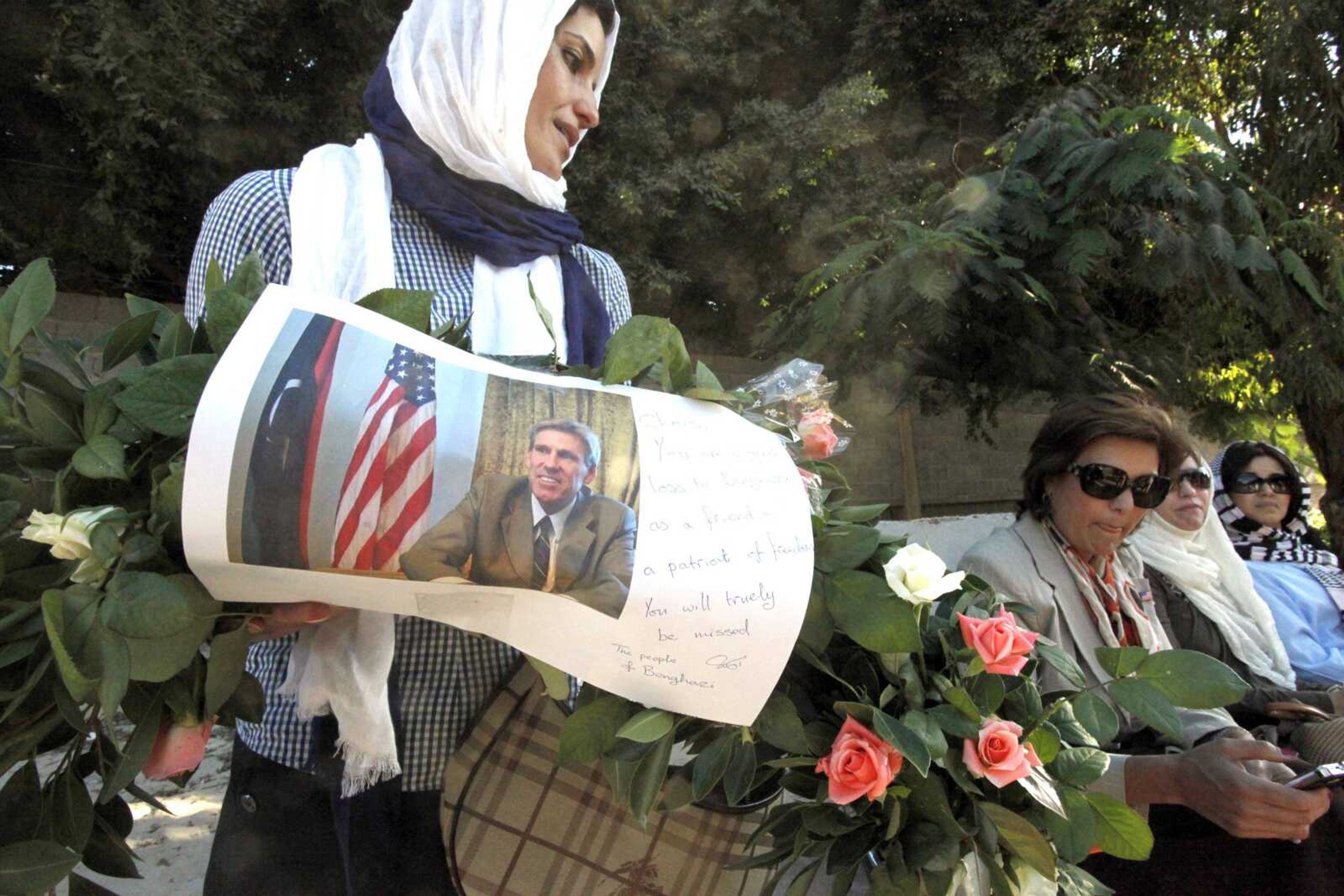 A Libyan woman carries a wreath with a photo of U.S. ambassador Chris Stevens on it as she and other Libyan and American women gather Monday to pay their respects to the victims of last week&#8217;s attack on the U.S. consulate in Benghazi, Libya. (Mohammad Hannon ~ Associated Press)