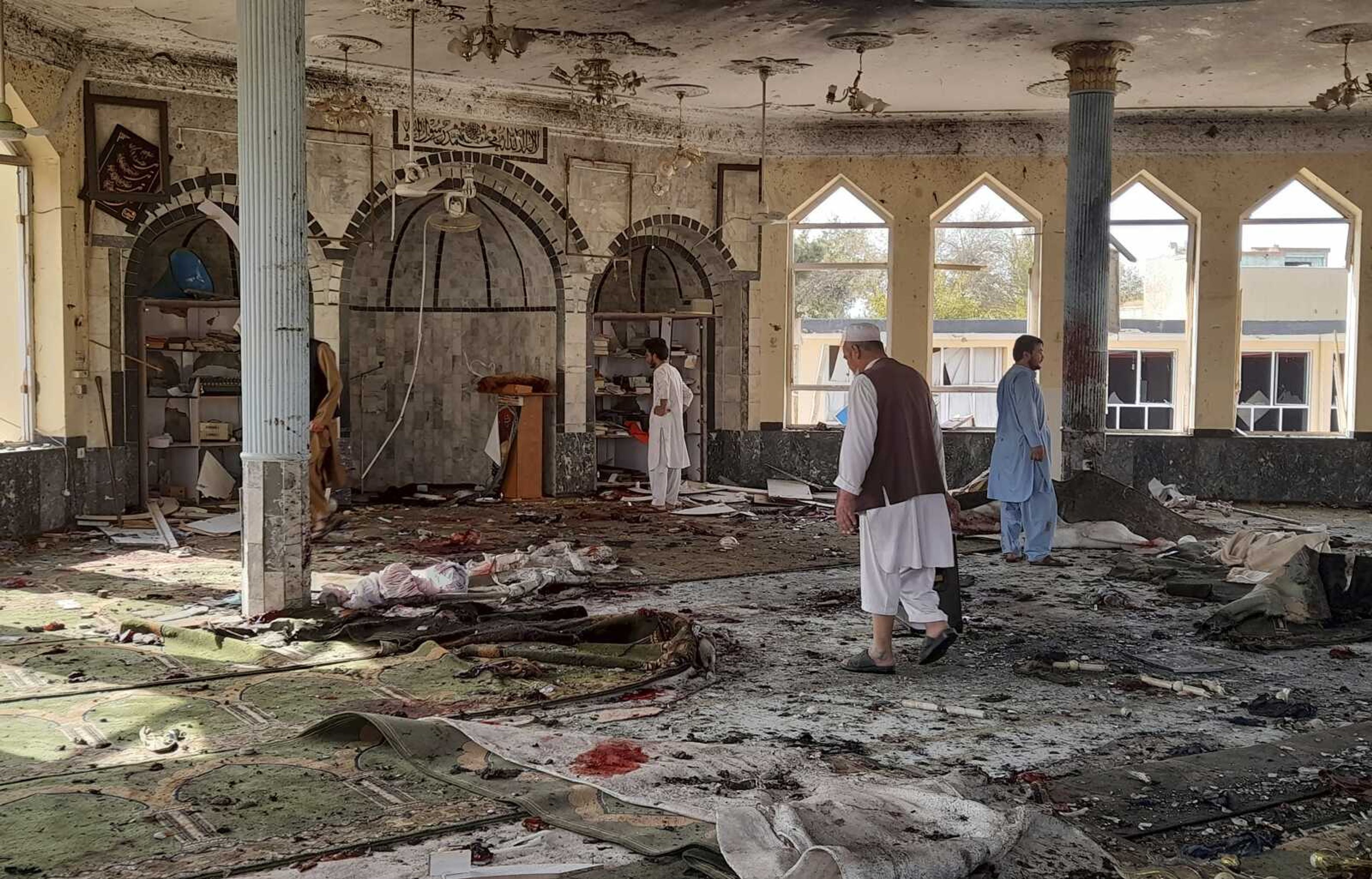 People inspect the inside of a mosque following a bombing in Kunduz province northern Afghanistan, Friday, Oct. 8, 2021. A powerful explosion in the mosque frequented by a Muslim religious minority in northern Afghanistan on Friday has left several casualties, witnesses and the Taliban's spokesman said. (AP Photo/Abdullah Sahil)