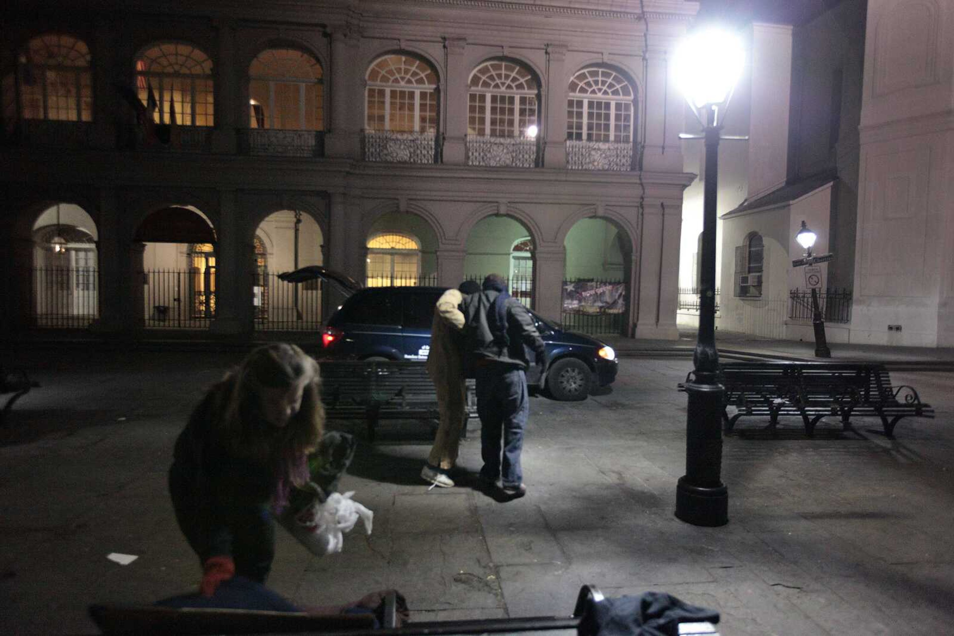 Katy Quigley, left, and Calvin Lee, center, of the abandoned buildings outreach team of Unity of Greater New Orleans, help a homeless person bundled up against the cold in Jackson Square in New Orleans. (Gerald Herbert ~ Associated Press)