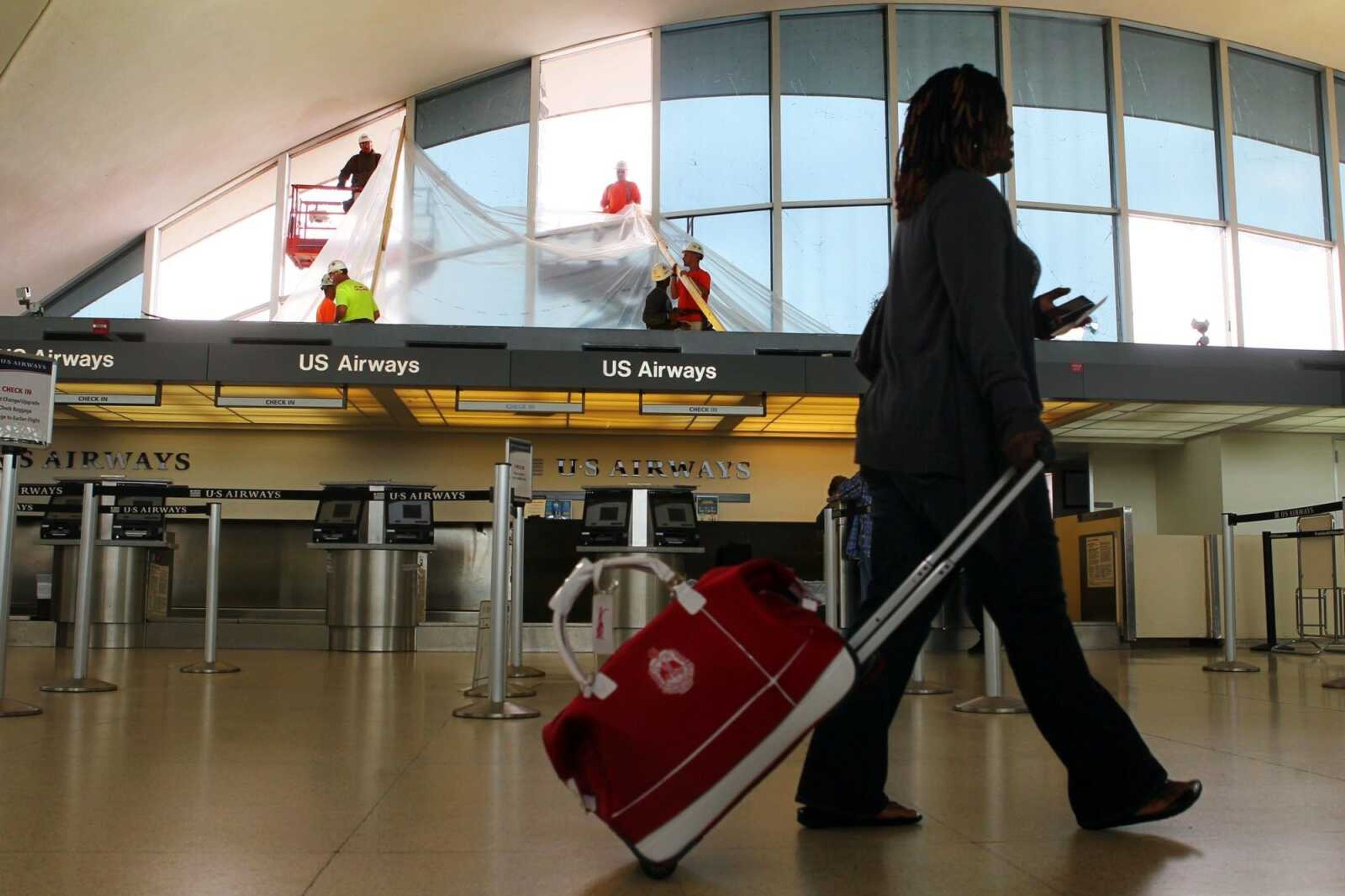 Workers with BAM Contracting work to cover the broken windows above the U.S. Airways booth Sunday at Lambert International Airport in St. Louis.  (Emily Rasinski/St. Louis Post-Dispatch)