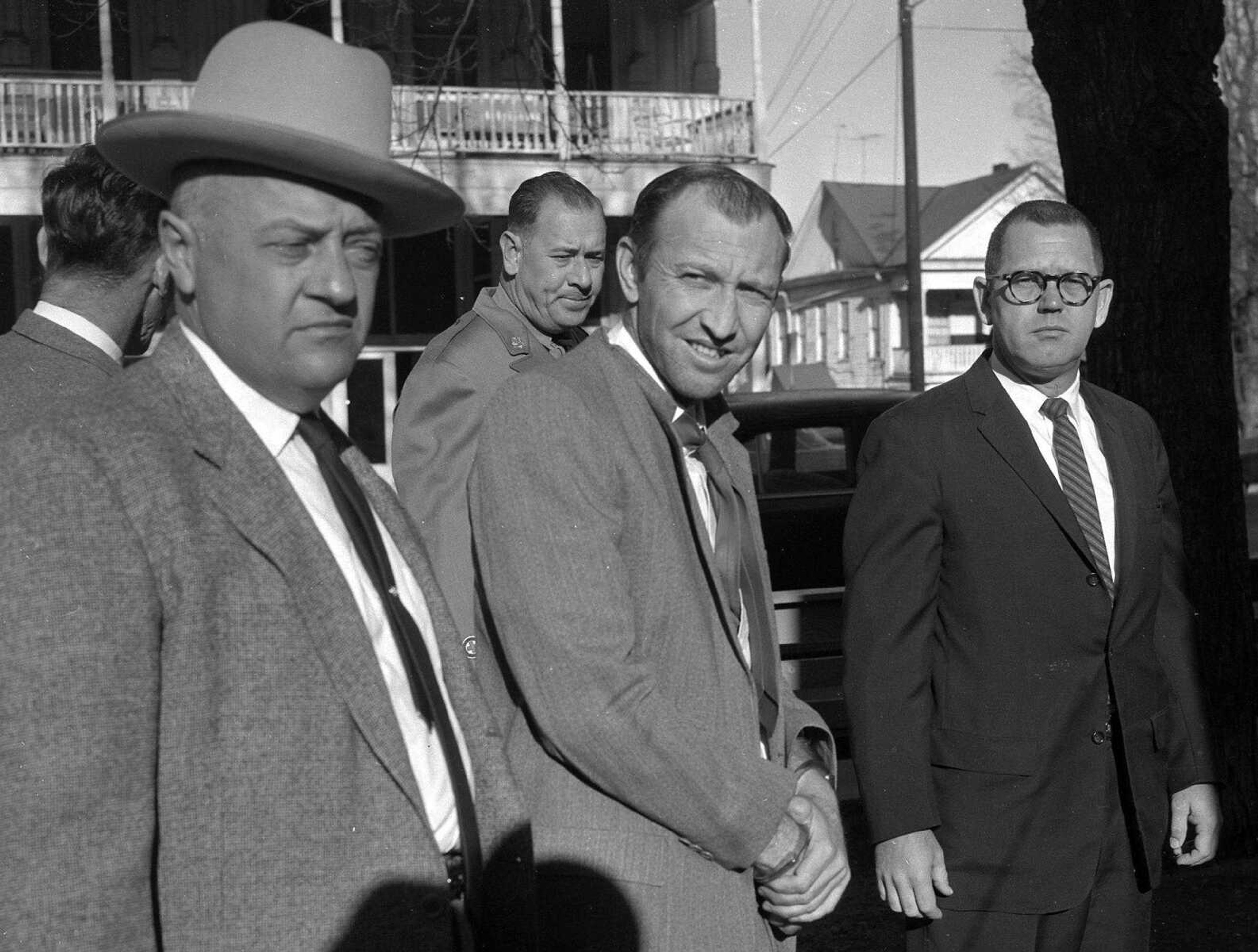 Douglas Wayne Thompson of Bakersfield, Calif., center, was led into Circuit Court at Marble Hill this morning for his trial on charges of the fatal shooting of Herbert L. Goss, Cape Girardeau auxiliary policeman, last March 10. At left is Sheriff Frank Matthews of Bollinger County, Trooper Frank C. Schiebel is at rear and Jay Nations, Cape-Bollinger County juvenile officer, at right. (Published Thursday, Dec. 7, 1961, pg. 1)