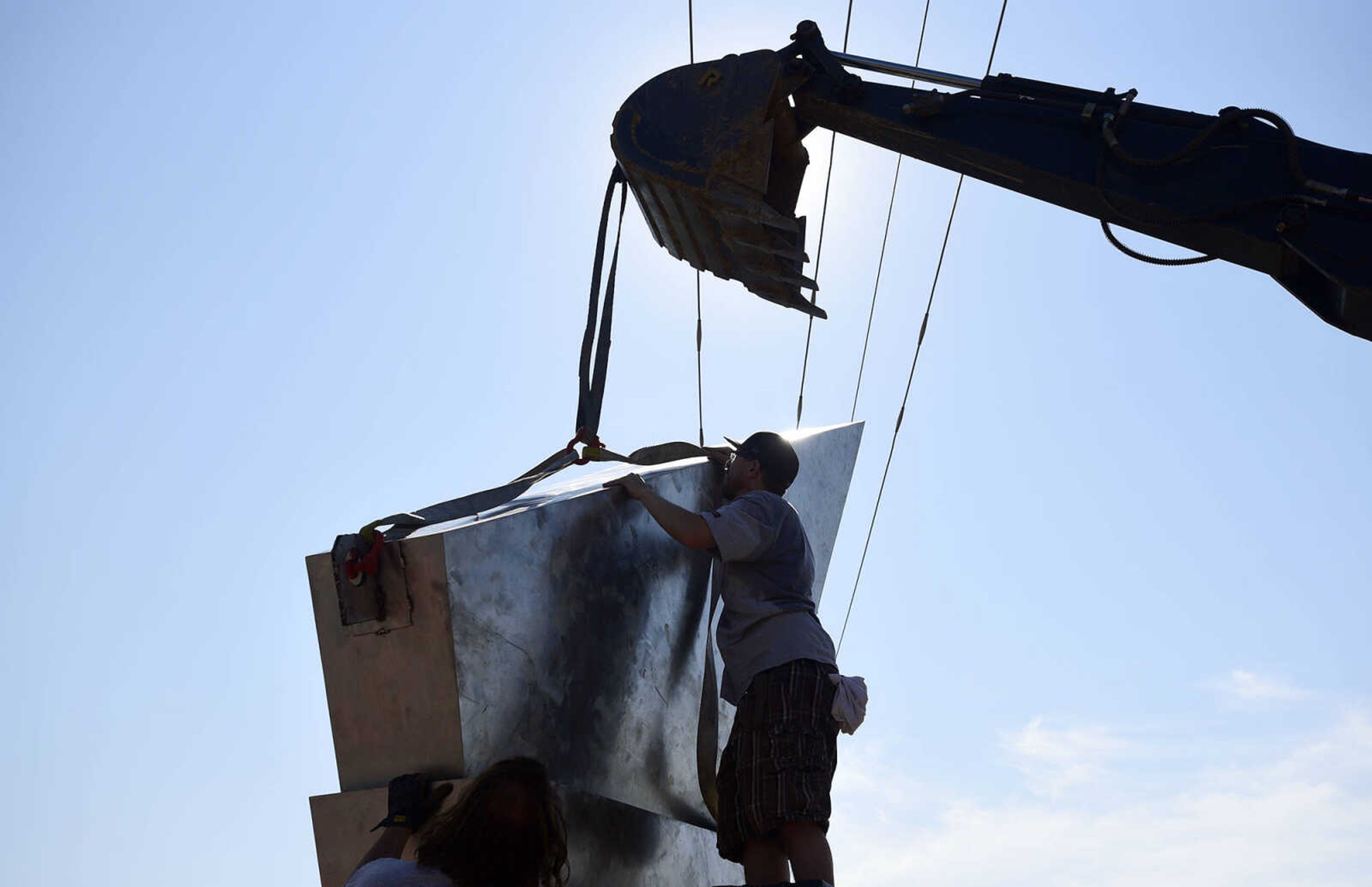 Chris Wubbena adjusts the straps around a section of his 14-foot sculpture, "Commence" to lift for installation in the Fountain Street roundabout on Monday, July 24, 2017, near the River Campus in Cape Girardeau.