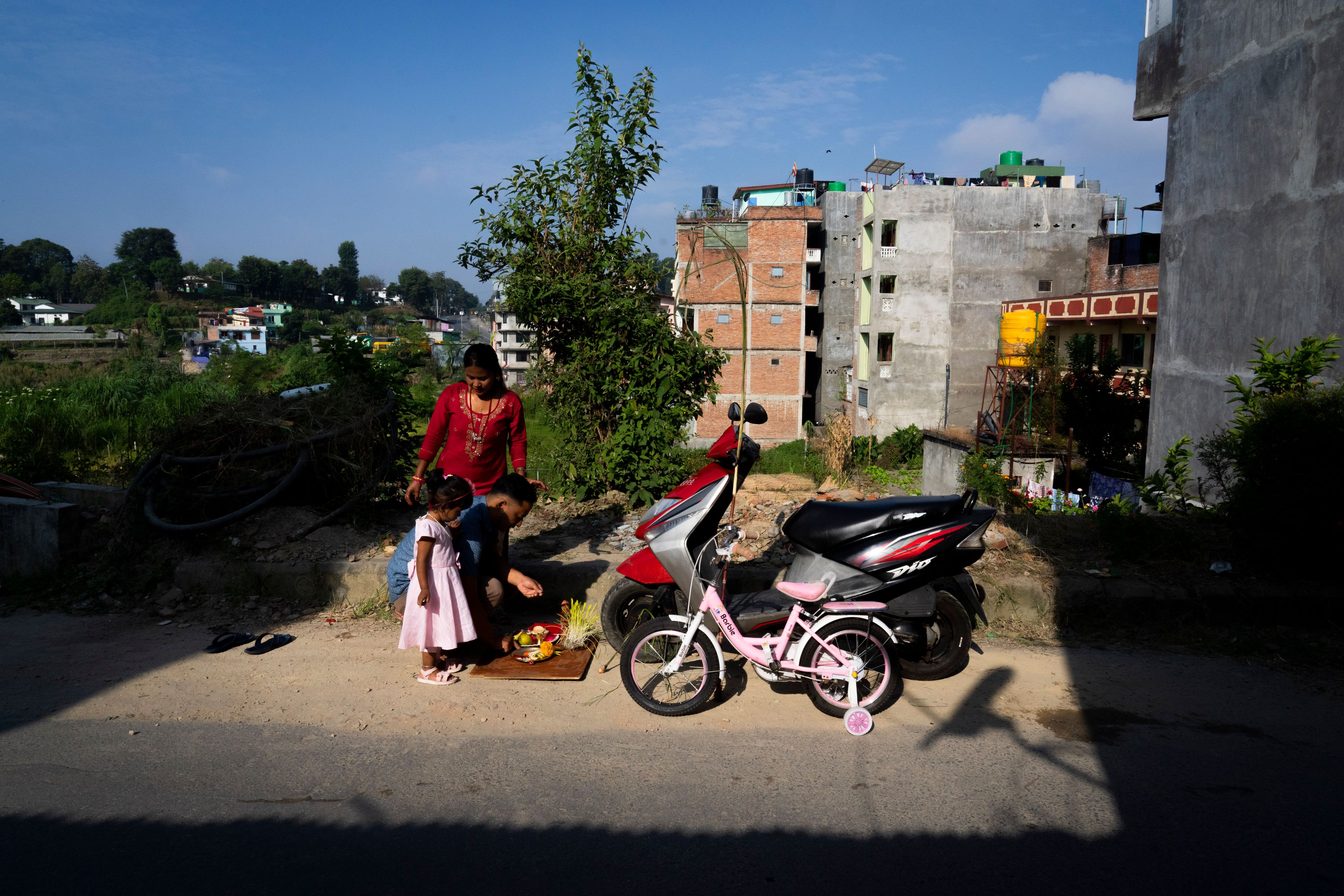 A family performs rituals to theirs vehicles during Dashain festival in Bhaktapur, Nepal, Friday, Oct. 11, 2024. The festival commemorates the slaying of a demon king by Hindu goddess Durga, marking the victory of good over evil. (AP Photo/Niranjan Shrestha)