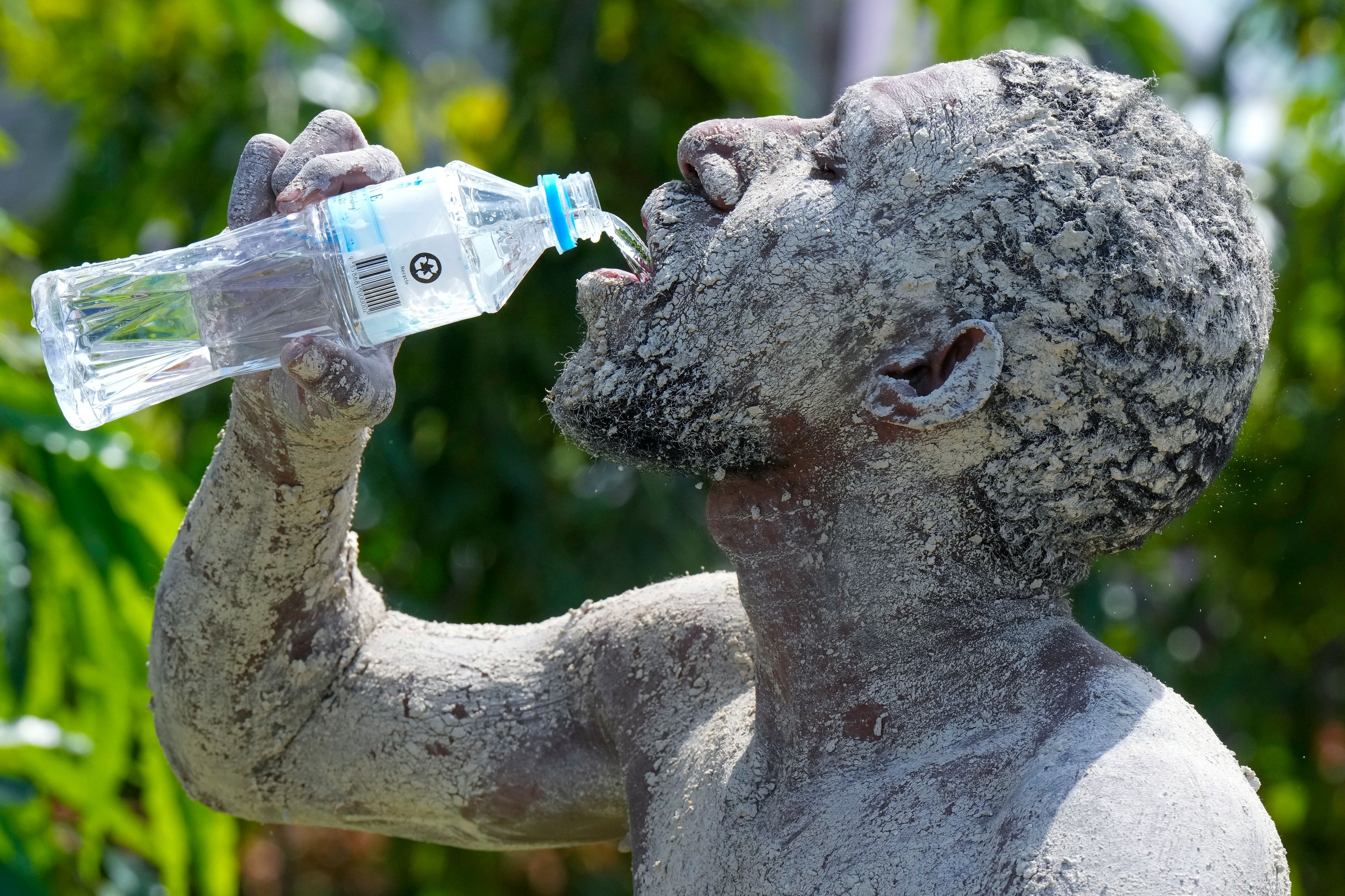 An Asaro mudman has a drink of water as Pope Francis gives an address during his meeting with young people at the Sir John Guise Stadium in Port Moresby, Papua New Guinea, Monday, Sept. 9, 2024. (AP Photo/Mark Baker)