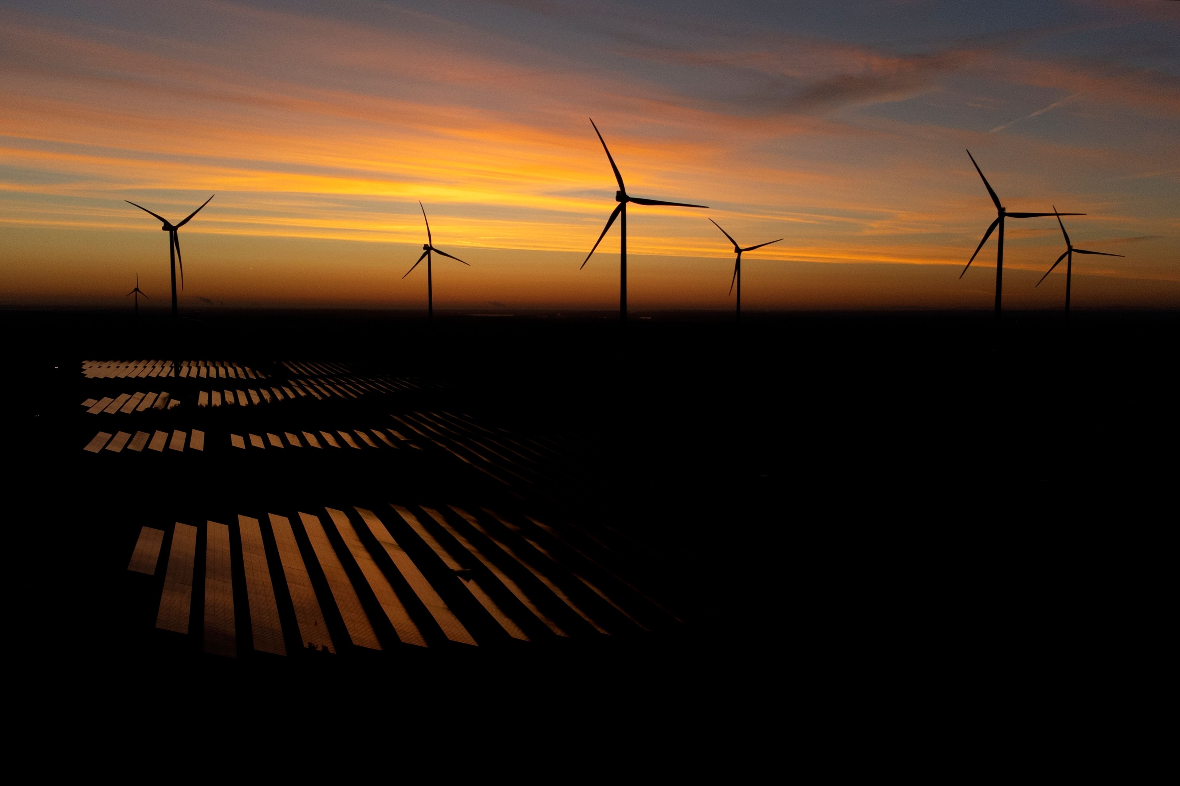 Wind turbines operate as the sun rises at the Klettwitz Nord solar energy park near Klettwitz, Germany, Wednesday, Oct. 16, 2024. (AP Photo/Matthias Schrader)