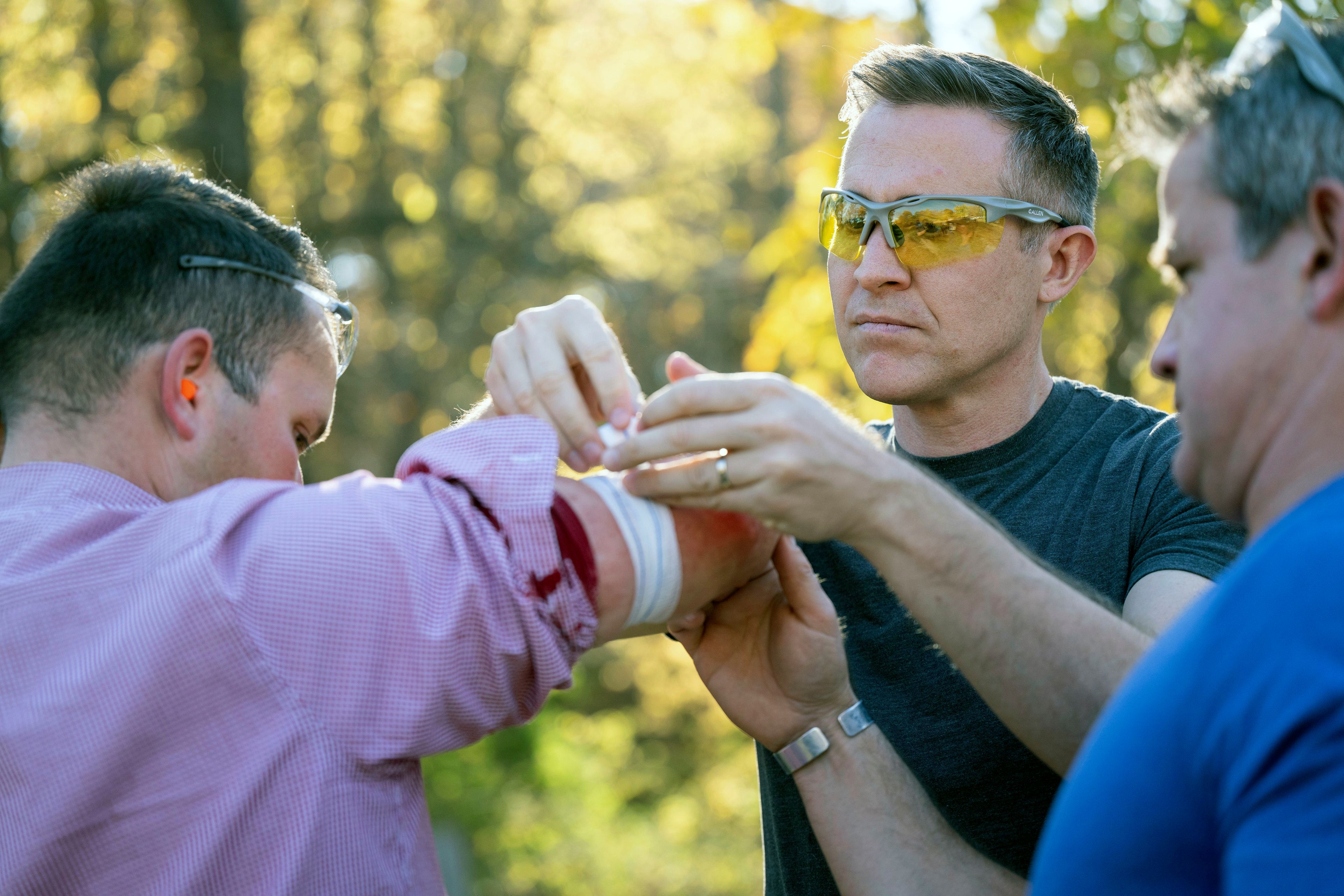 Democratic U.S. senate candidate Lucas Kunce, center, applies first aid to KSHB reporter Ryan Gamboa, left, after Gamboa was struck by a metal fragment during a sport shooting campaign event Tuesday, Oct. 22, 2024 in Holt, Missouri. (Dominick Williams/The Kansas City Star via AP)