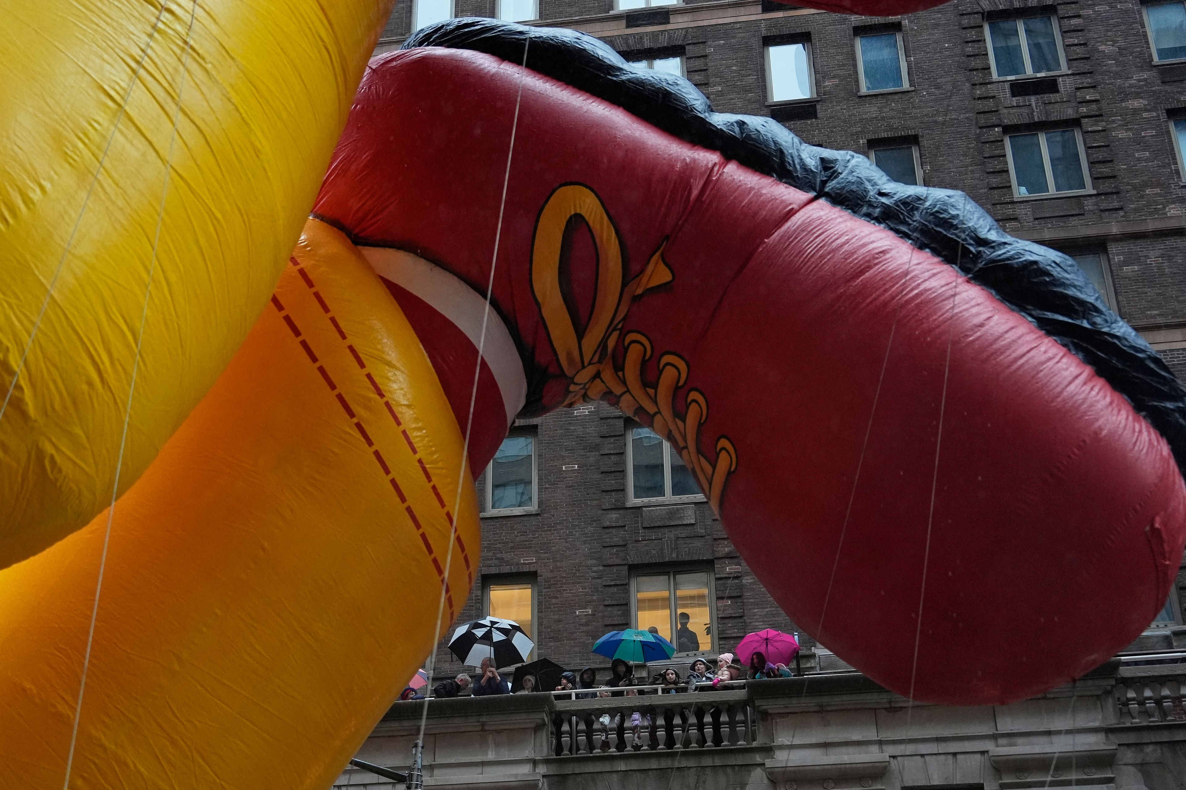 Spectators watch from an apartment building terrace as handlers pull the Ronald McDonald balloon down Sixth Avenue during the Macy's Thanksgiving Day Parade, Thursday, Nov. 28, 2024, in New York. (AP Photo/Julia Demaree Nikhinson)