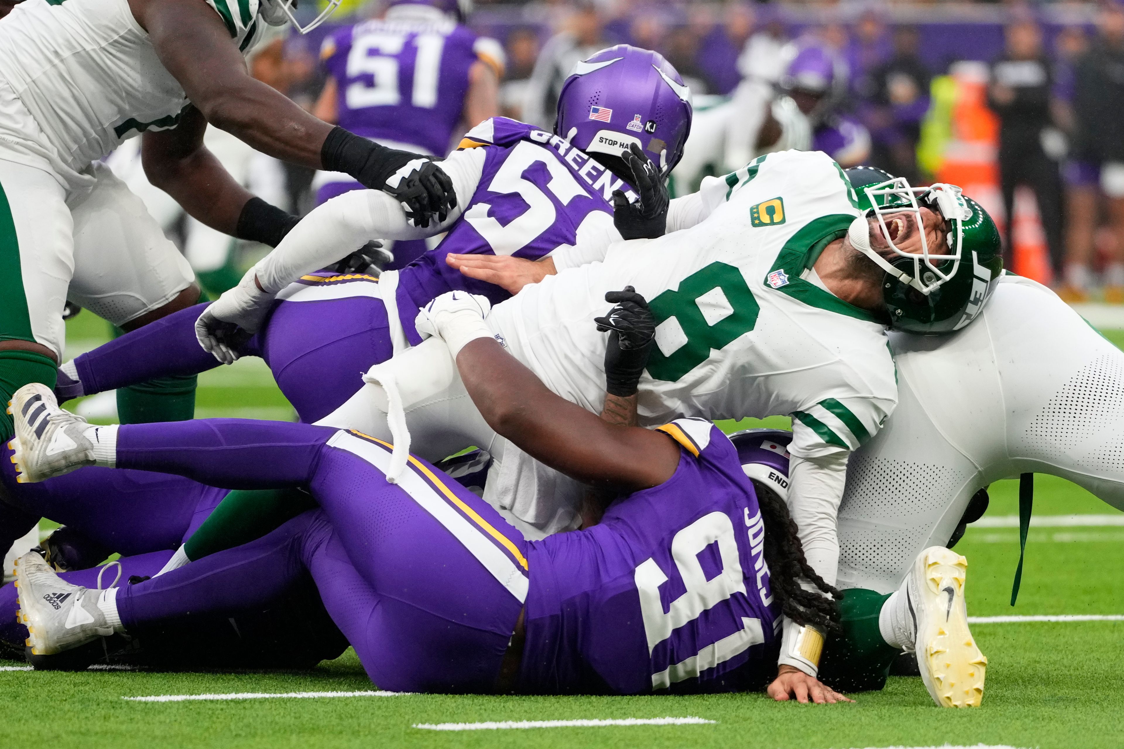 New York Jets quarterback Aaron Rodgers (8), right, reacts as he is tackled during the second half of an NFL football game against the Minnesota Vikings, Sunday, Oct. 6, 2024, at the Tottenham Hotspur stadium in London. (AP Photo/Kirsty Wigglesworth)