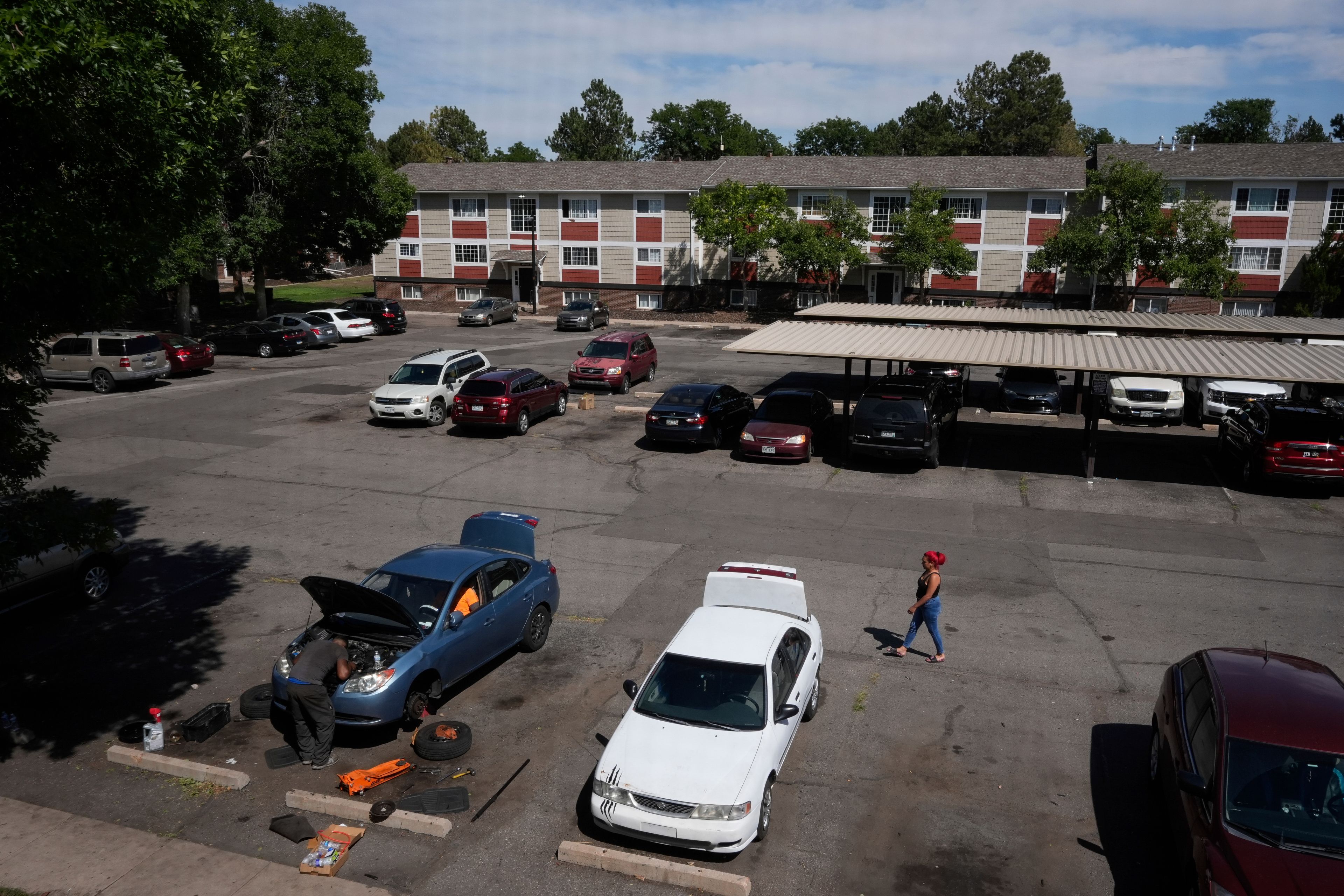 Gabriela Ramírez, right, walks over to her two friends who were trying to repair a mechanical issue with her car Thursday, Aug. 29, 2024, in Aurora, Colo. (AP Photo/Godofredo A. Vásquez)