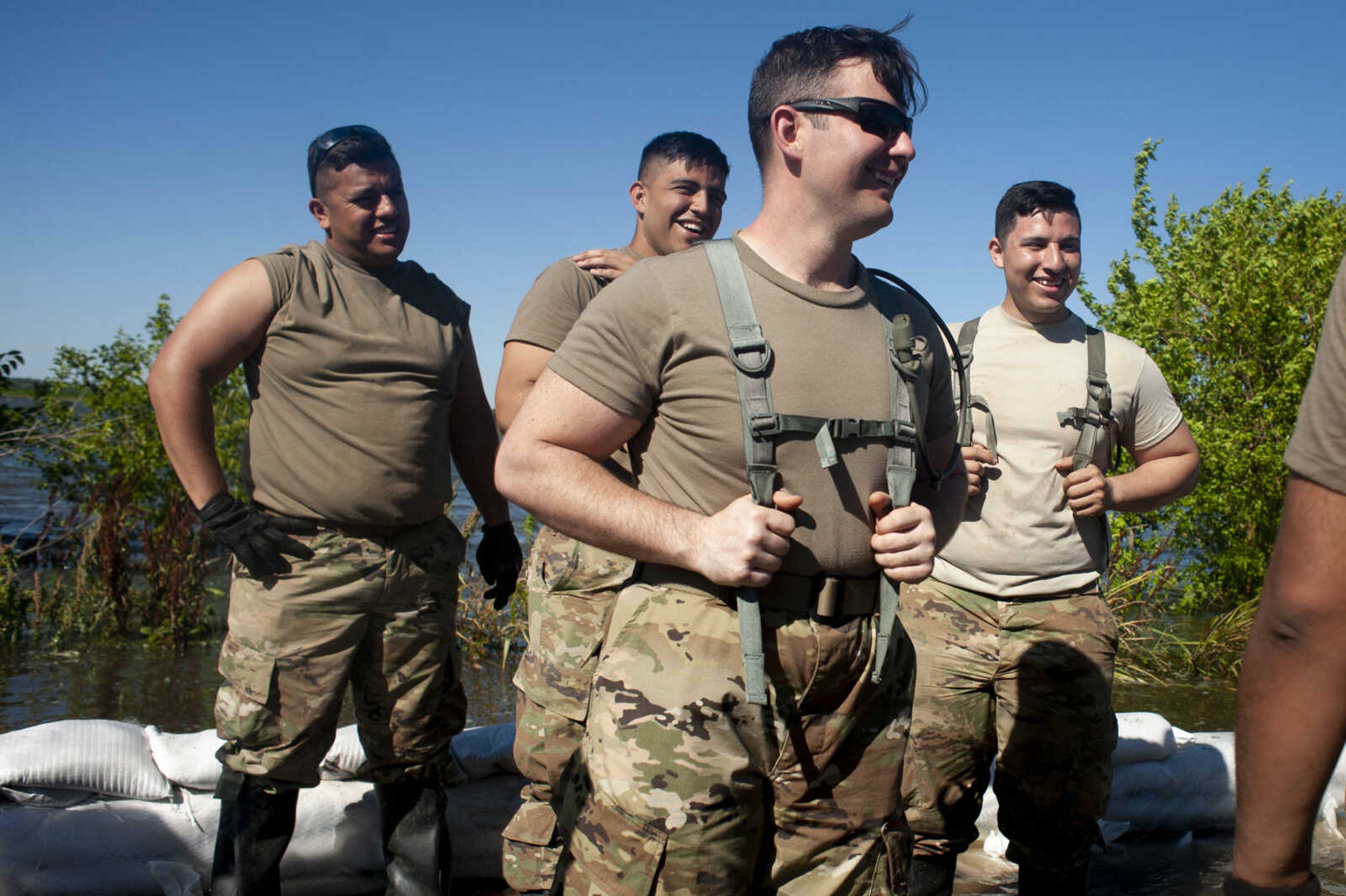 Illinois National Guard member Alex Harden, in front, and fellow members, back from left, Arturo Martinez, Jesse Aguilera and Luis Lopez, laugh during a pause in helping build up sandbag barriers to hold back floodwaters Monday, June 10, 2019, along Brookwood Drive in East Cape Girardeau, Illinois.