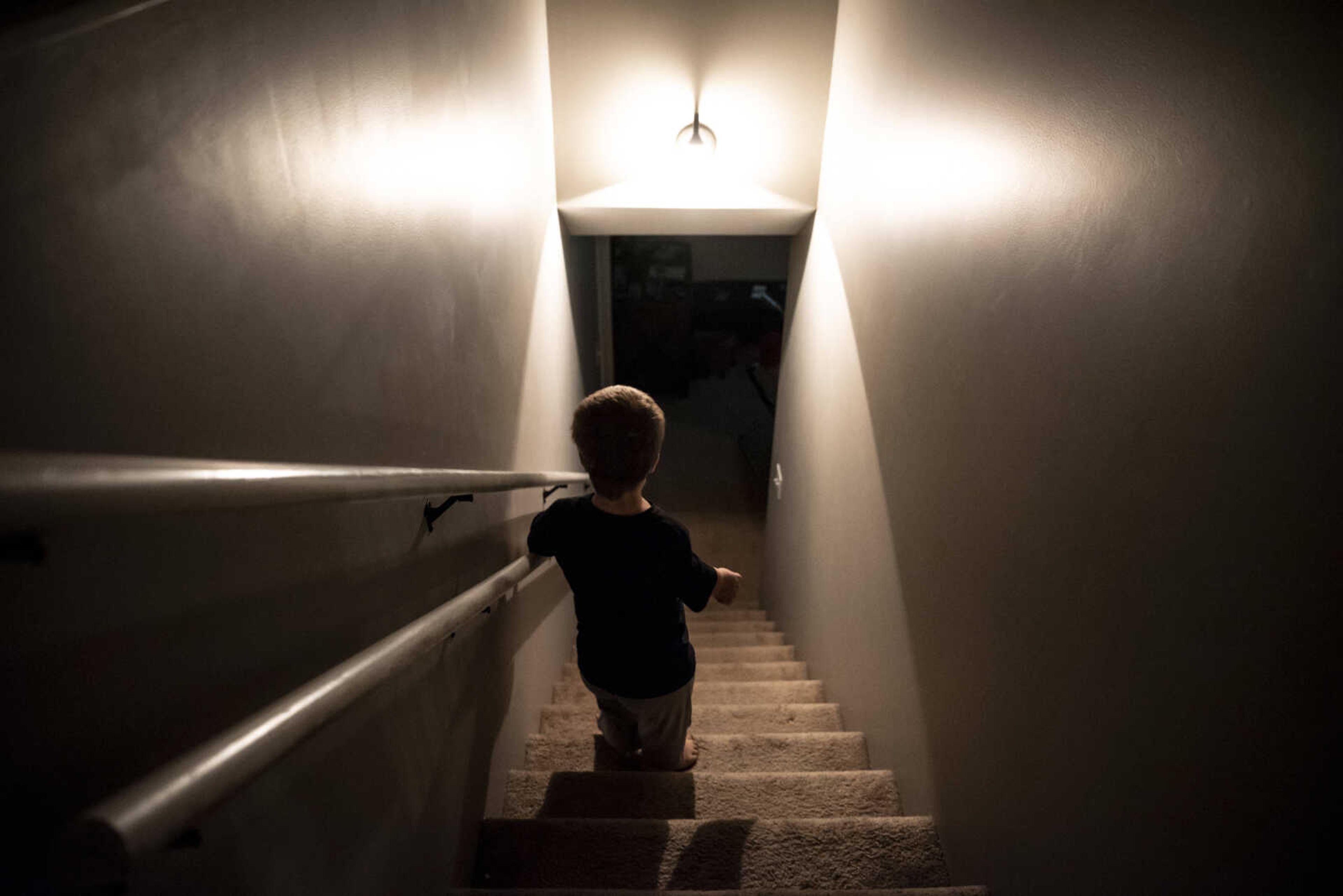 Izaac Pursley uses the handrail installed specifically for his height in his family's basement stairway Oct. 1, 2018, in Jackson.